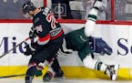 The Carolina Hurricanes' Jaccob Slavin (74) upends the Minnesota Wild's Jason Pominville (29) as he slams him into the boards during the third period 
