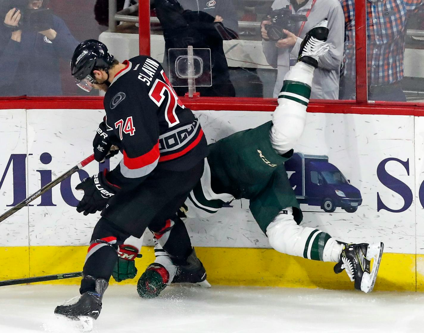 The Carolina Hurricanes' Jaccob Slavin (74) upends the Minnesota Wild's Jason Pominville (29) as he slams him into the boards during the third period at PNC Arena in Raleigh, N.C., on Thursday, March 16, 2017. The Canes won, 3-1. (Chris Seward/Raleigh News & Observer/TNS) ORG XMIT: 1199101