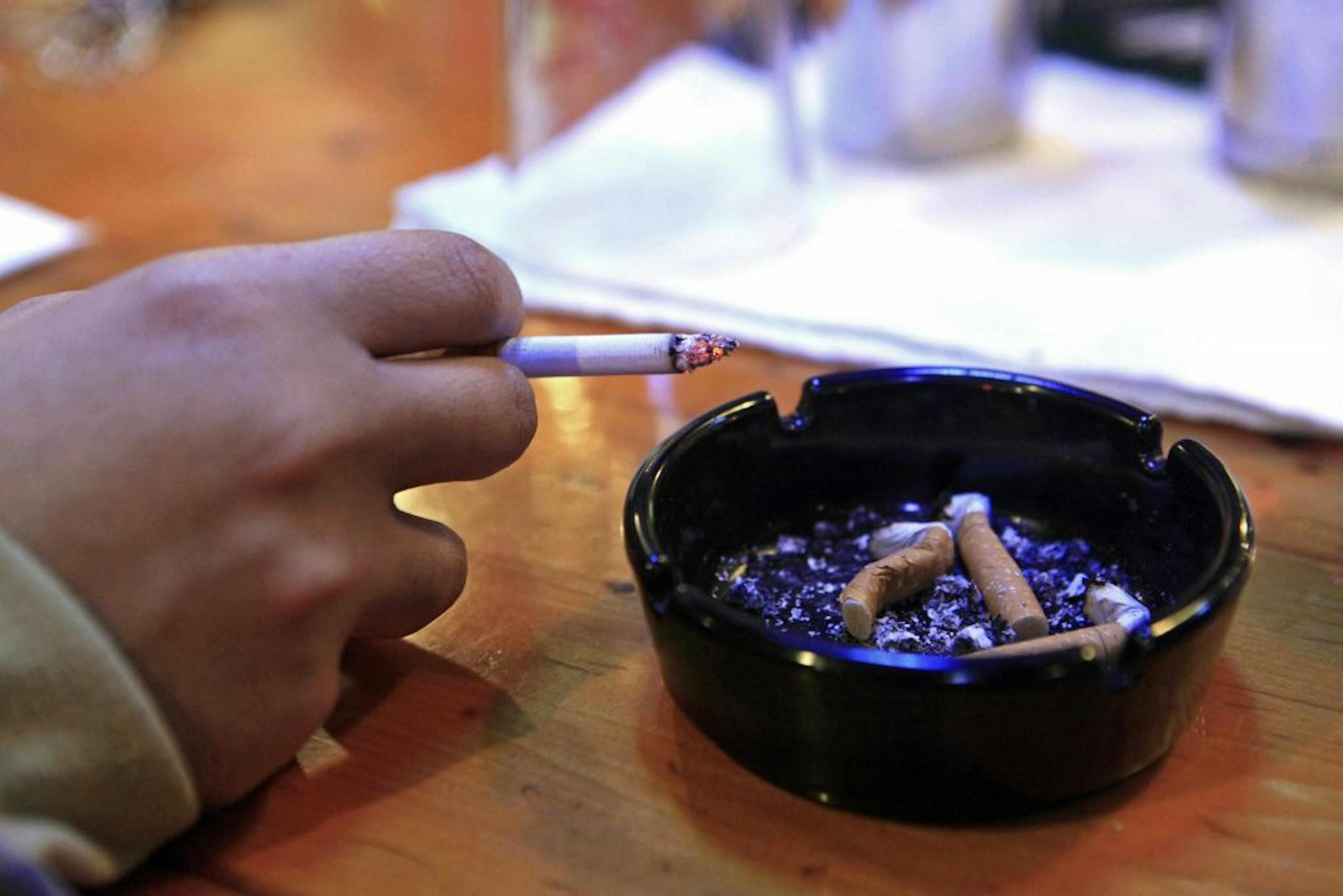 FILE - In this file photo made Dec. 17, 2009, a person holds a cigarette in Durham, N.C. A year after a new law put tobacco regulation in the hands of the Food and Drug Administration, one thing is clear: It will likely be years before any of the most aggressive steps to reduce deaths from smoking might happen.