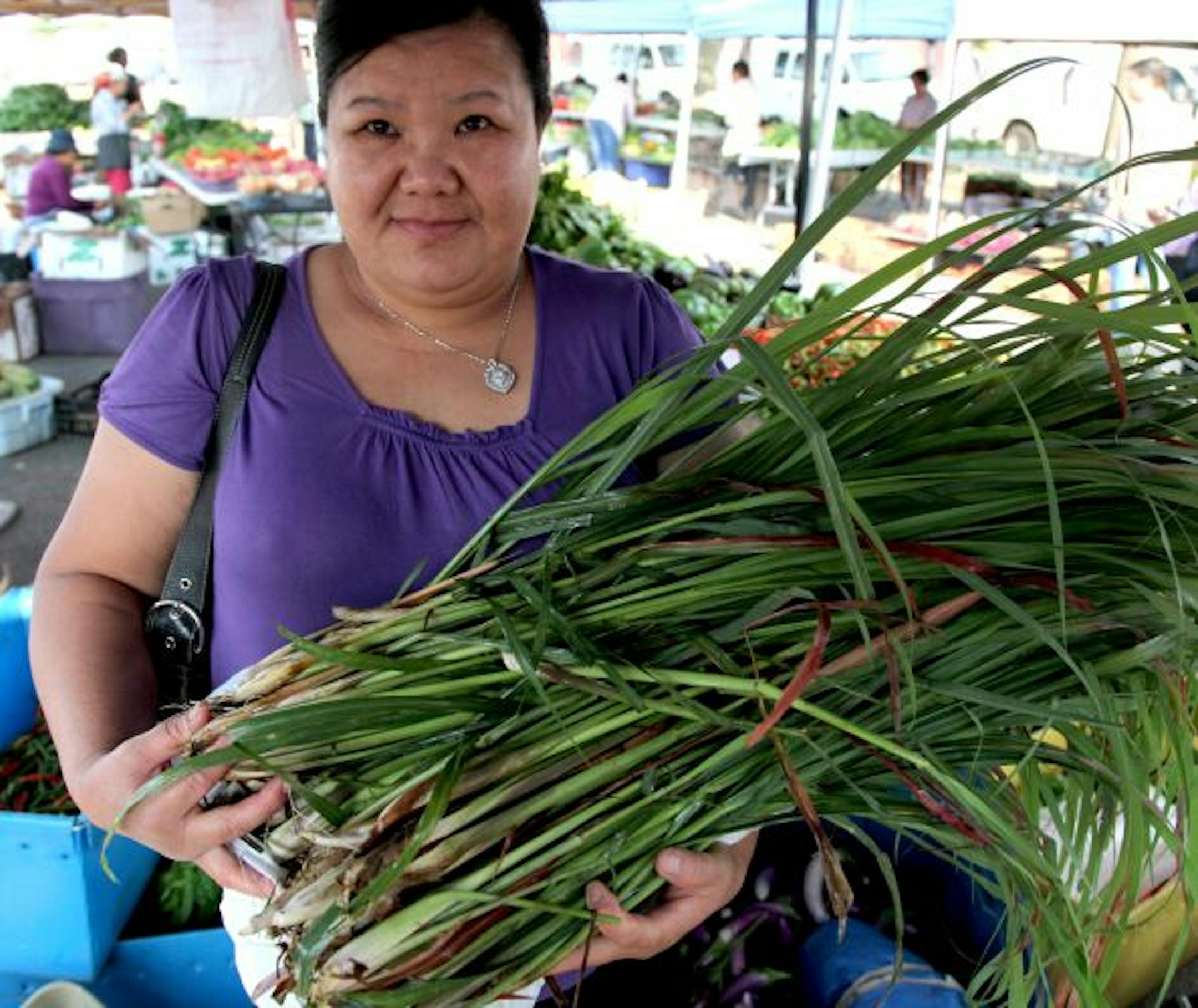 Mai Ly shops the farmers market for produce, including the lemongrass she holds, which she will bundle up and freeze if there is extra.