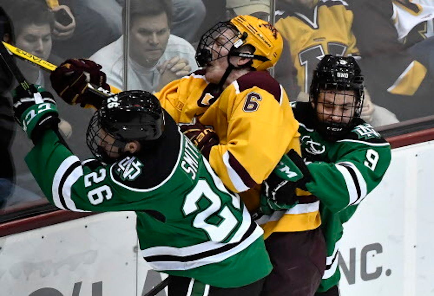 Minnesota Golden Gophers right defender Ryan Collins (6) took a hard check from North Dakota Fighting Hawks forward Cole Smith (26) and defenseman Dixon Bowen (9) in the first period Saturday.