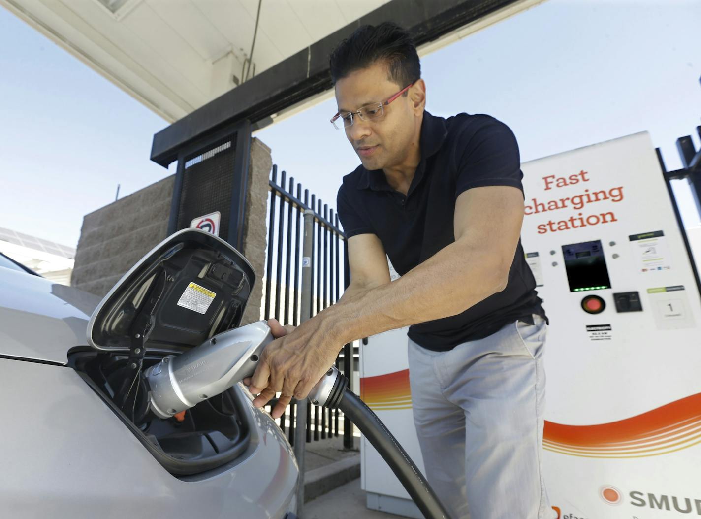 In this Thursday, Sept. 17, 2015 file photo, Darshan Brahmbhatt, plugs a charger into his electric vehicle at the Sacramento Municipal Utility District charging station in Sacramento, Calif. ORG XMIT: MER0f292e6e74f6db30dd1c930c5bd12