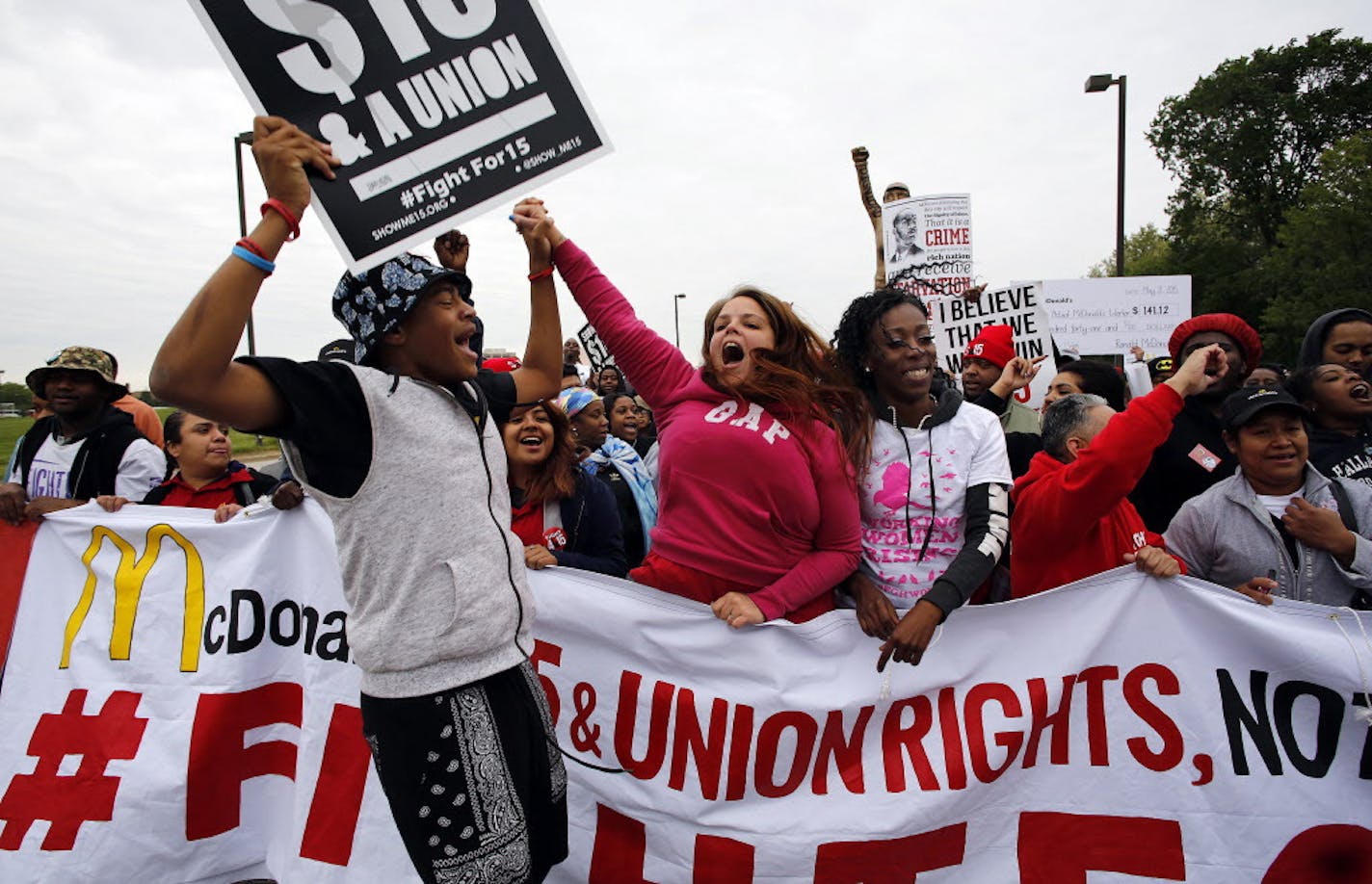 David Bates of New Orleans gets the crowd jumping while holding hands with Beth Schaffer, a crew member from Charleston, S.C., and Ashona Osborne of Pittsburgh during a rally at the gate of the McDonald's campus on Thursday, May 21, 2015, in Oak Brook, Ill. (Chuck Berman//Chicago Tribune/TNS) ORG XMIT: 1168289