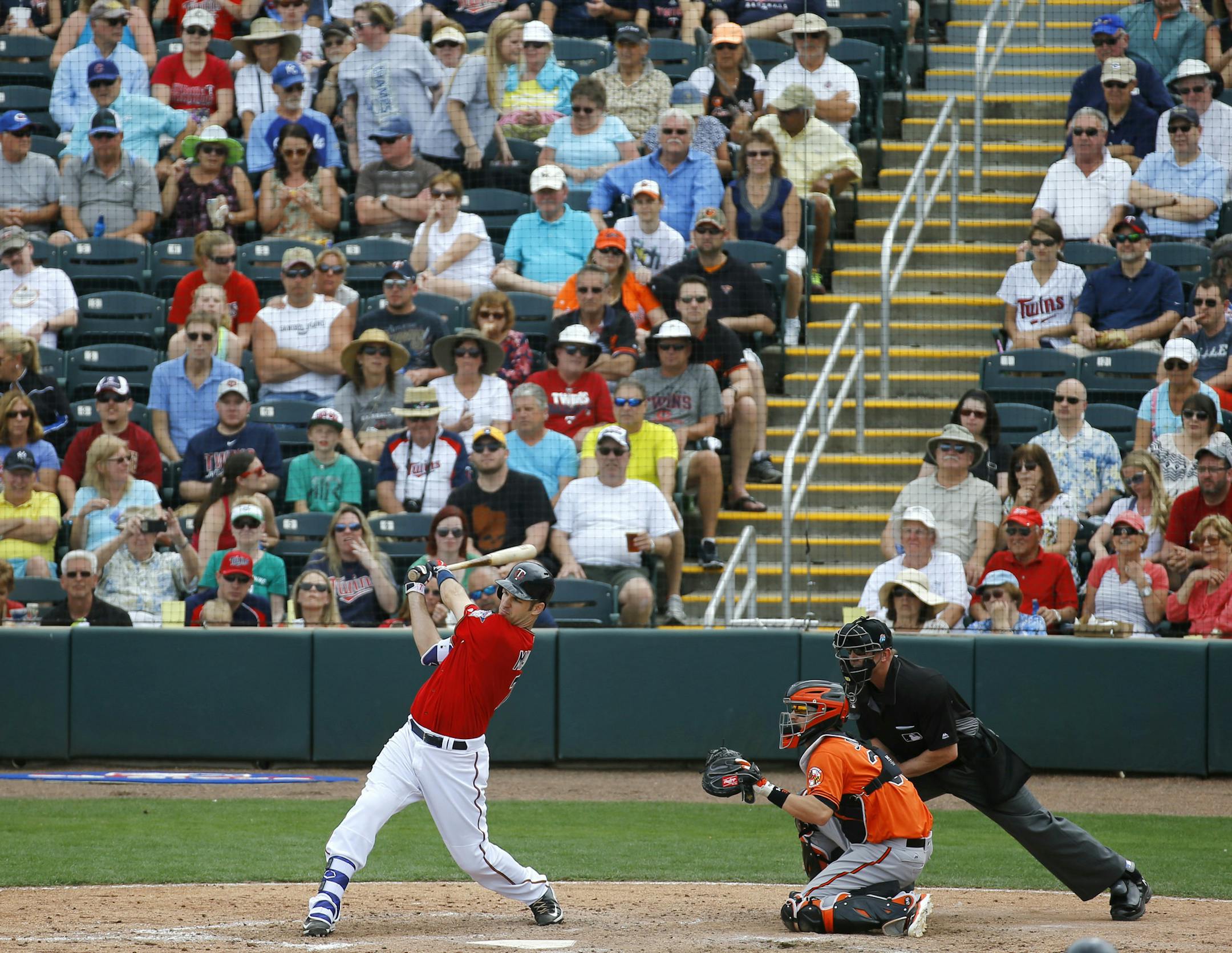 Minnesota Twins' Joe Mauer, left, hits a sacrifice groundout in front of Baltimore Orioles catcher Caleb Joseph and home plate umpire Jeff Kellogg in the fifth inning of a spring training baseball game in Fort Myers, Fla., Saturday, March 5, 2016. Kurt Suzuki scored on the play. (AP Photo/Patrick Semansky)
