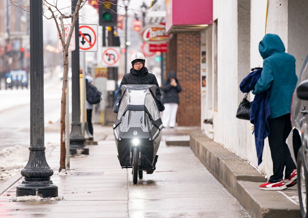 Kevin Ha rides his cargo bike towards a Burger King to pick-up a delivery food order near the University of Minnesota in Minneapolis. 
