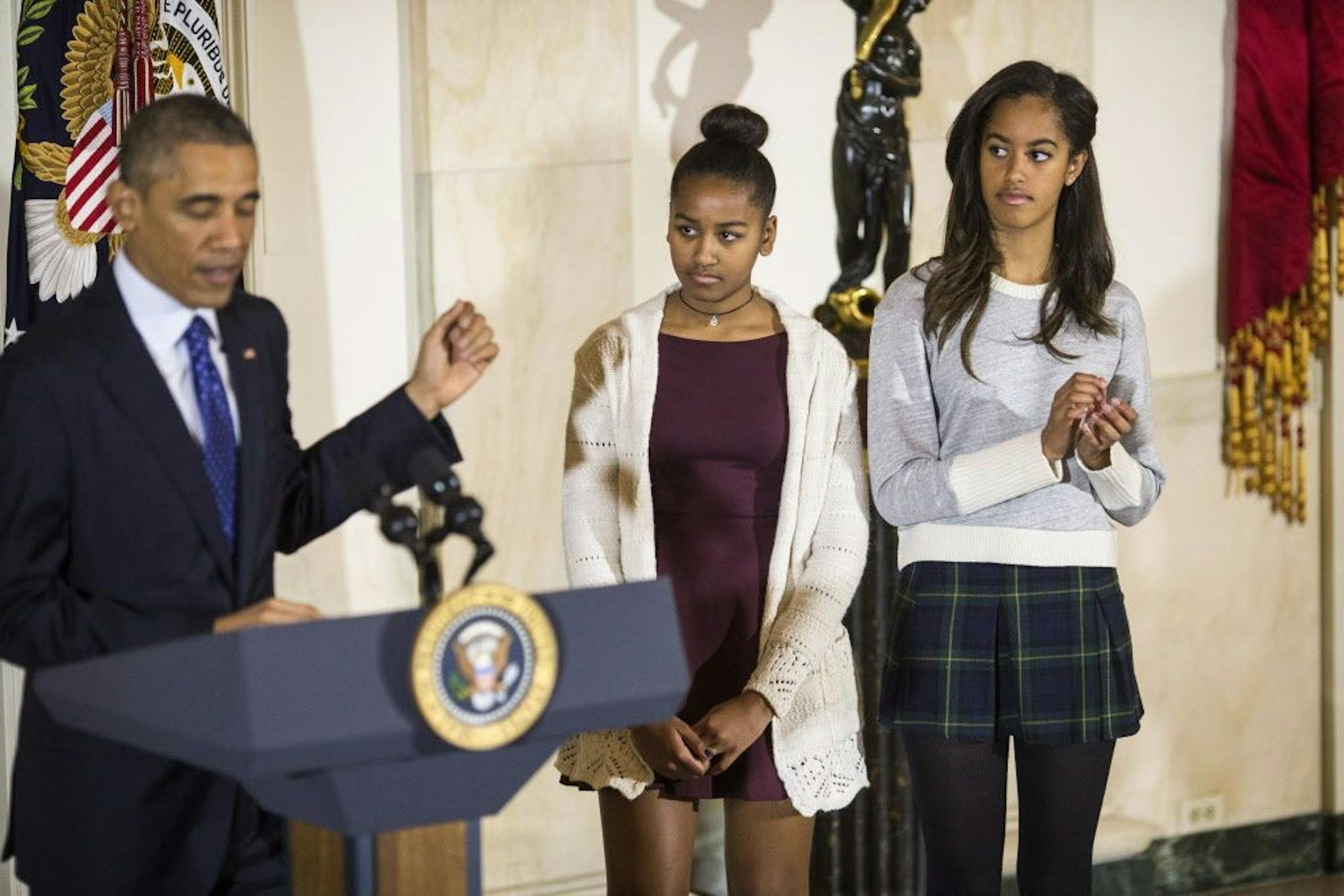 President Barack Obama pardons Cheese, the National Thanksgiving Turkey, as his daughters, Sasha and Malia, right, look on.