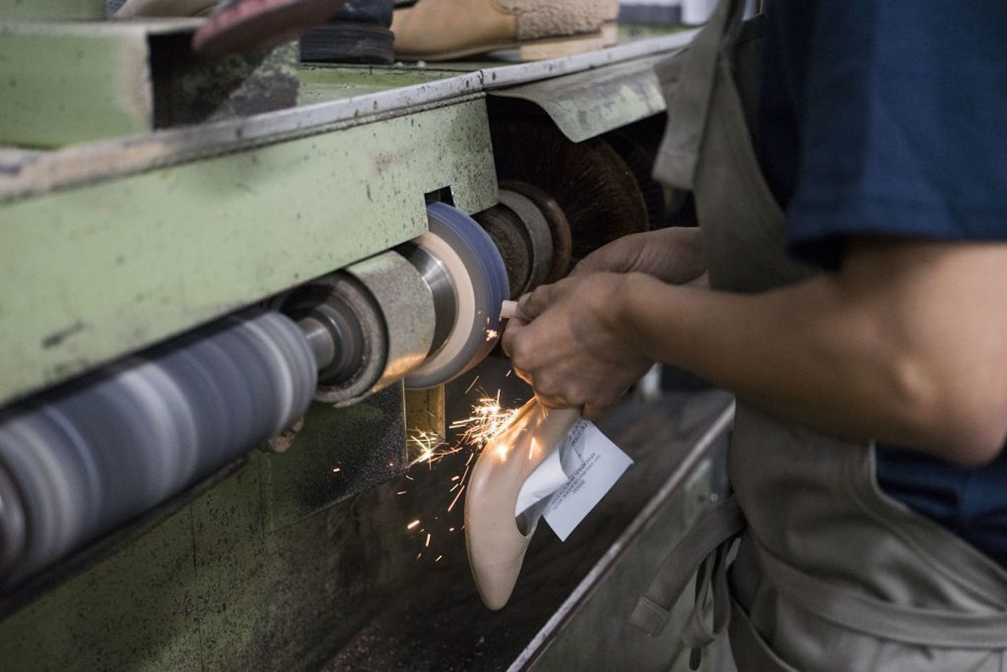 A worker sands down the bottom of a heel at the repair shop in Minneapolis.