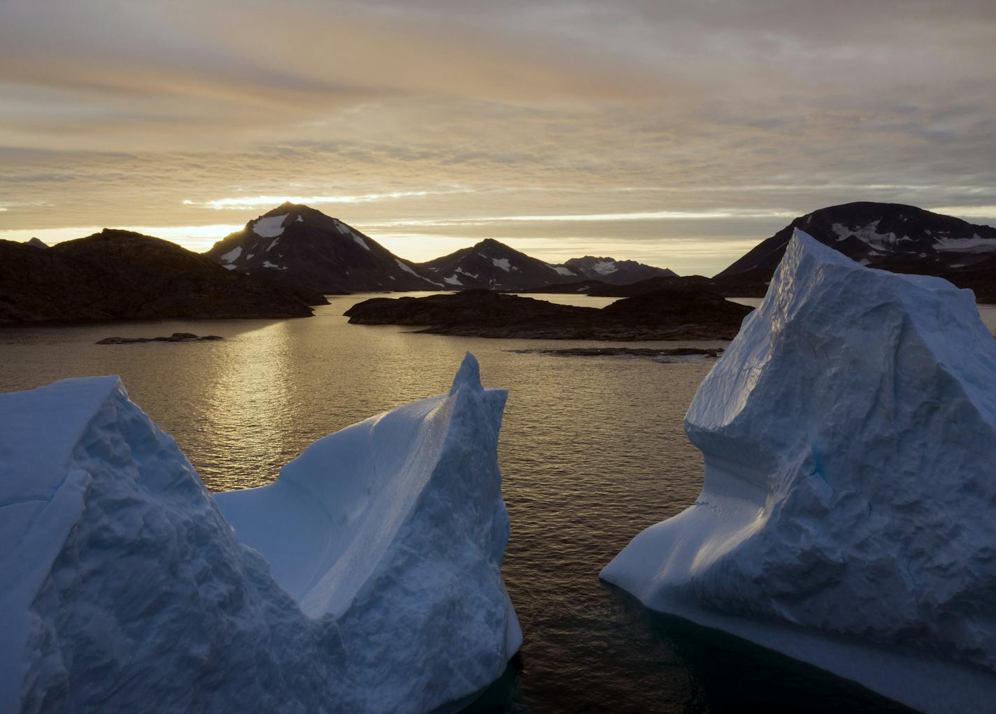 FILE - This early Friday, Aug. 16, 2019 file photo shows an aerial view of large Icebergs floating as the sun rises near Kulusuk, Greenland. Greenland has been melting faster in the last decade, and this summer, it has seen two of the biggest melts on record since 2012. A special United Nations-affiliated oceans and ice report released on Wednesday, Sept. 24, 2019 projects three feet of rising seas by the end of the century, much fewer fish, weakening ocean currents, even less snow and ice, and