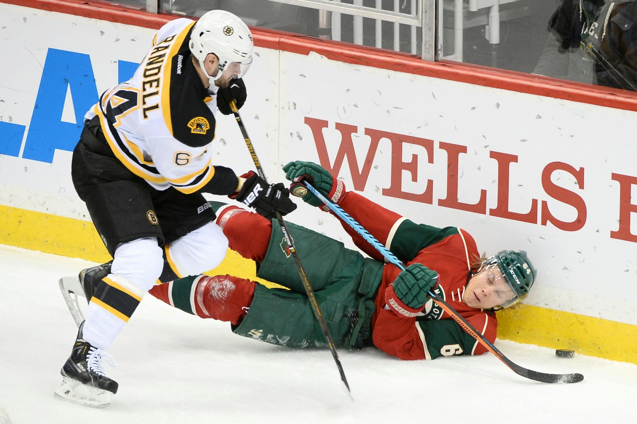Minnesota Wild center Mikael Granlund (64) fell to the ice while chasing the puck while being challenged by Boston Bruins right wing Tyler Randell (64) in the first period.