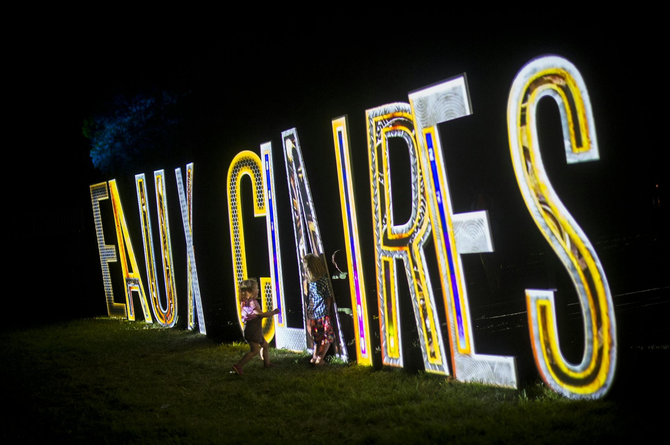 Children played by the illuminated Eaux Claires sign Saturday night during Bon Iver's set. ] Aaron Lavinsky • aaron.lavinsky@startribune.com The Eaux Claires Music & Art Festival was photographed Saturday, July 18, 2015 in Eau Claire, WI.