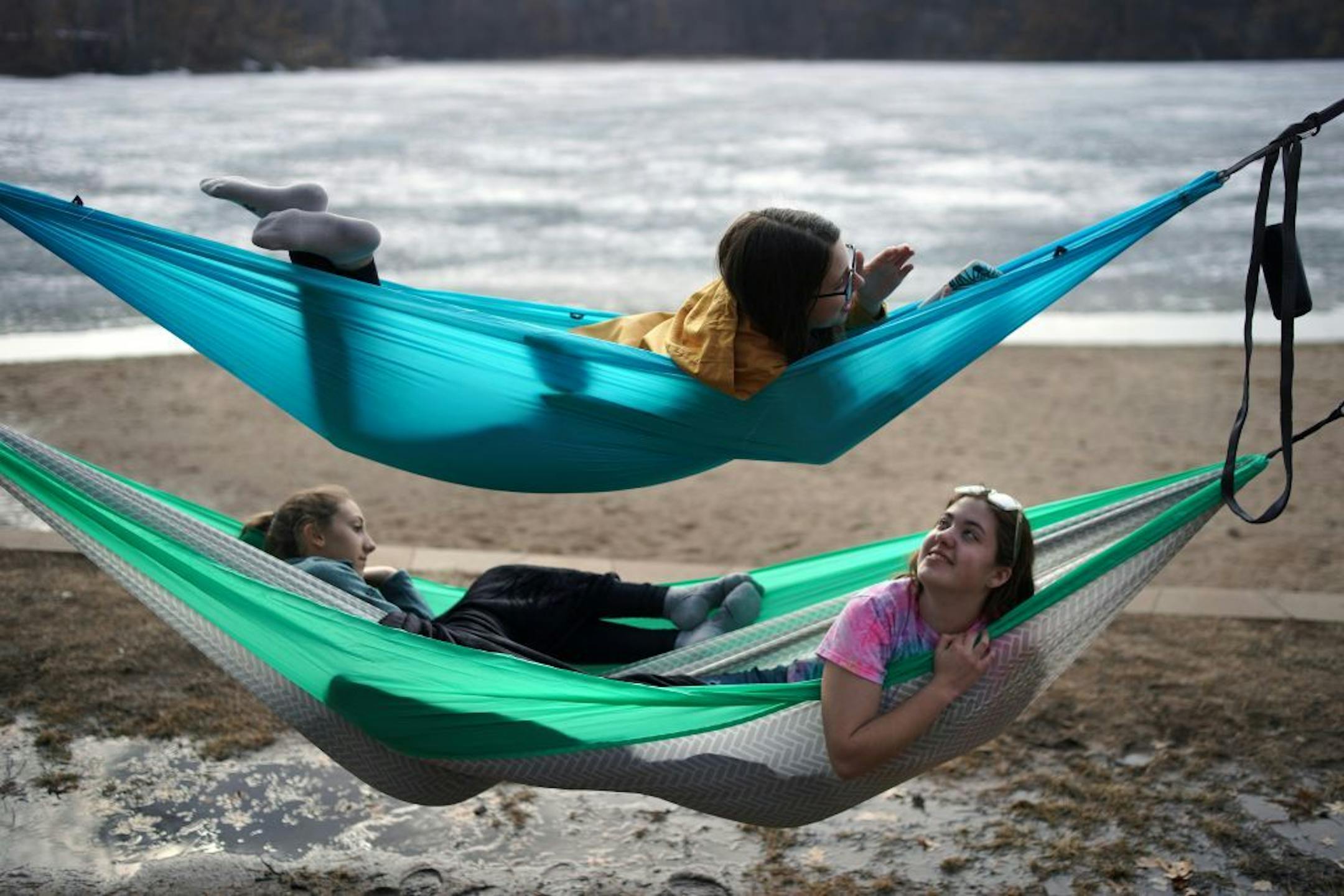 As temps climbed Wednesday, Rosemount High 10th-graders Erica Stockdale (bottom left) Emily Gadker (bottom right) and Arin Kujala (top) strung hammocks by frozen Schultze Lake in Lebanon Hills Regional Park in Eagan.