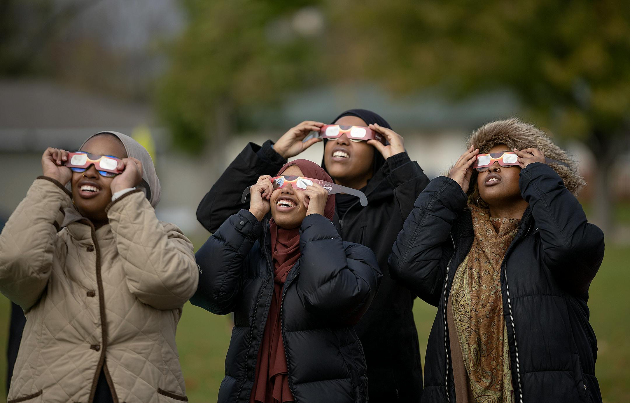 Young Muslim girls view the annular Eclipse as the clouds break during a viewing party at Commons Park in Fridley, Minn., on Saturday, Oct. 14, 2023.