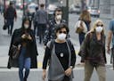 FILE - In this Nov. 9, 2018, file photo, people wear masks while walking through the Financial District in the smoke-filled air in San Francisco due t