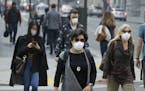 FILE - In this Nov. 9, 2018, file photo, people wear masks while walking through the Financial District in the smoke-filled air in San Francisco due t