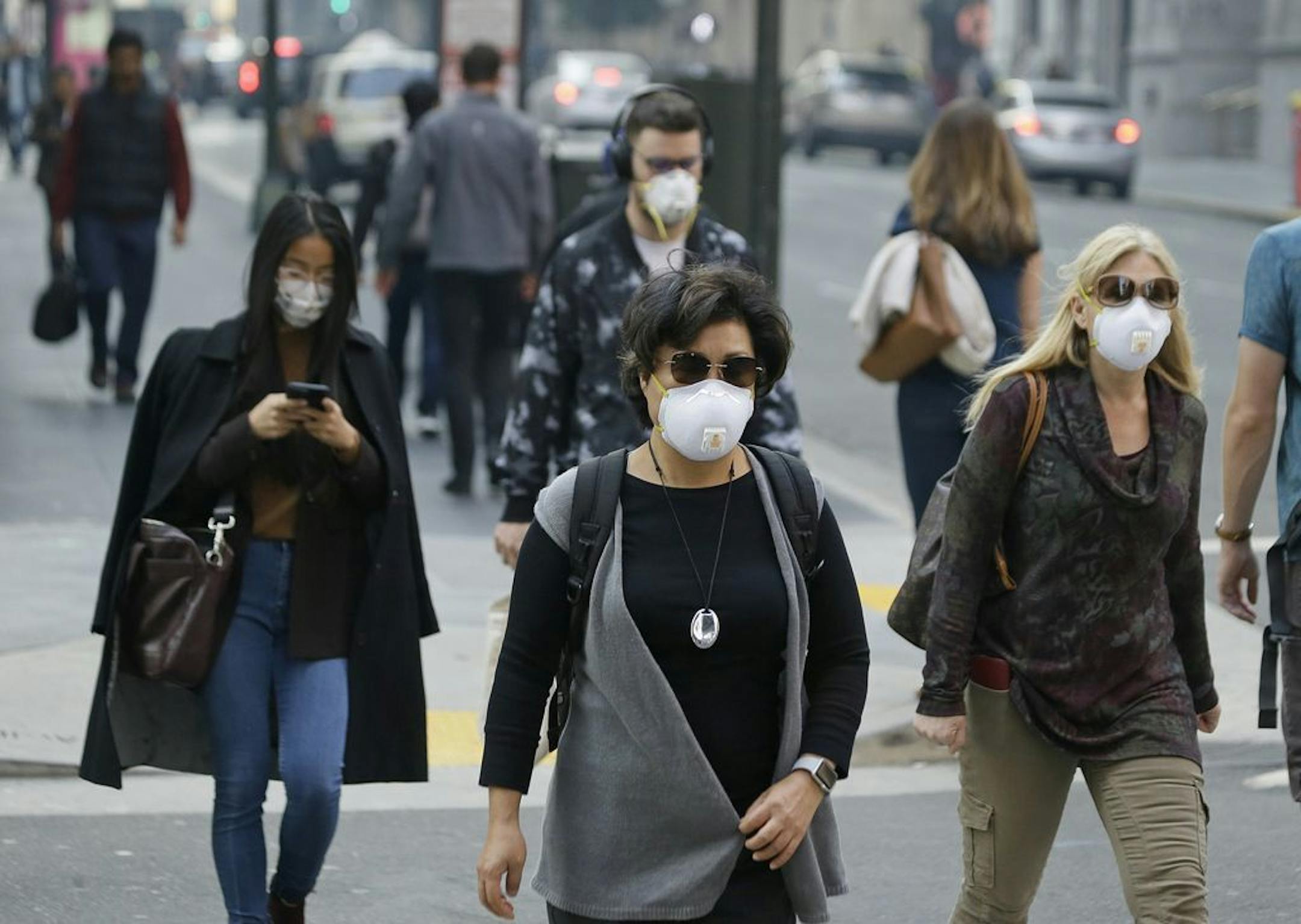 FILE - In this Nov. 9, 2018, file photo, people wear masks while walking through the Financial District in the smoke-filled air in San Francisco due to California wildfires. Tens of millions of people in the Western US face a growing health risk due to wildfires as more intense and frequent blazes churn out greater volumes of lung-damaging smoke, according to research scientists at NASA and several major universities.