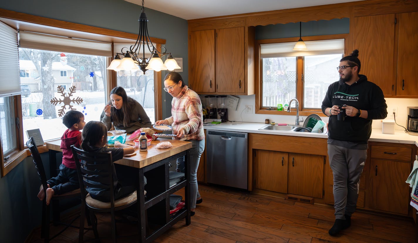 Kellie Basswood, center, put together an after school snack for the family as her partner William Lussier, right, warmed up with a cup of coffee Friday, Jan. 12, 2024 Champllin, Minn. First time homebuyer Kellie Basswood and her partner William Lussier were able to purchase this home with the help of the Mni Sota Fund, a wealth building nonprofit that works with Native families to help bridge the homeownership gap between white and Native Minnesotans. ] GLEN STUBBE • glen.stubbe@startribune.com