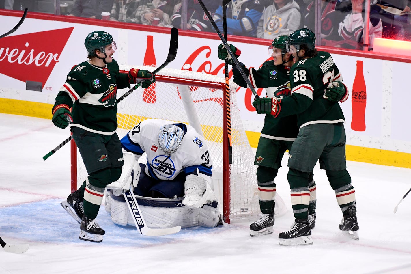 Minnesota Wild's Jared Spurgeon celebrates his goal on Winnipeg Jets goaltender Connor Hellebuyck (37) with Sam Steel and Ryan Hartman (38) during the first period of an NHL hockey game in Winnipeg, Manitoba, on Tuesday Dec. 27, 2022. (Fred Greenslade/The Canadian Press via AP)