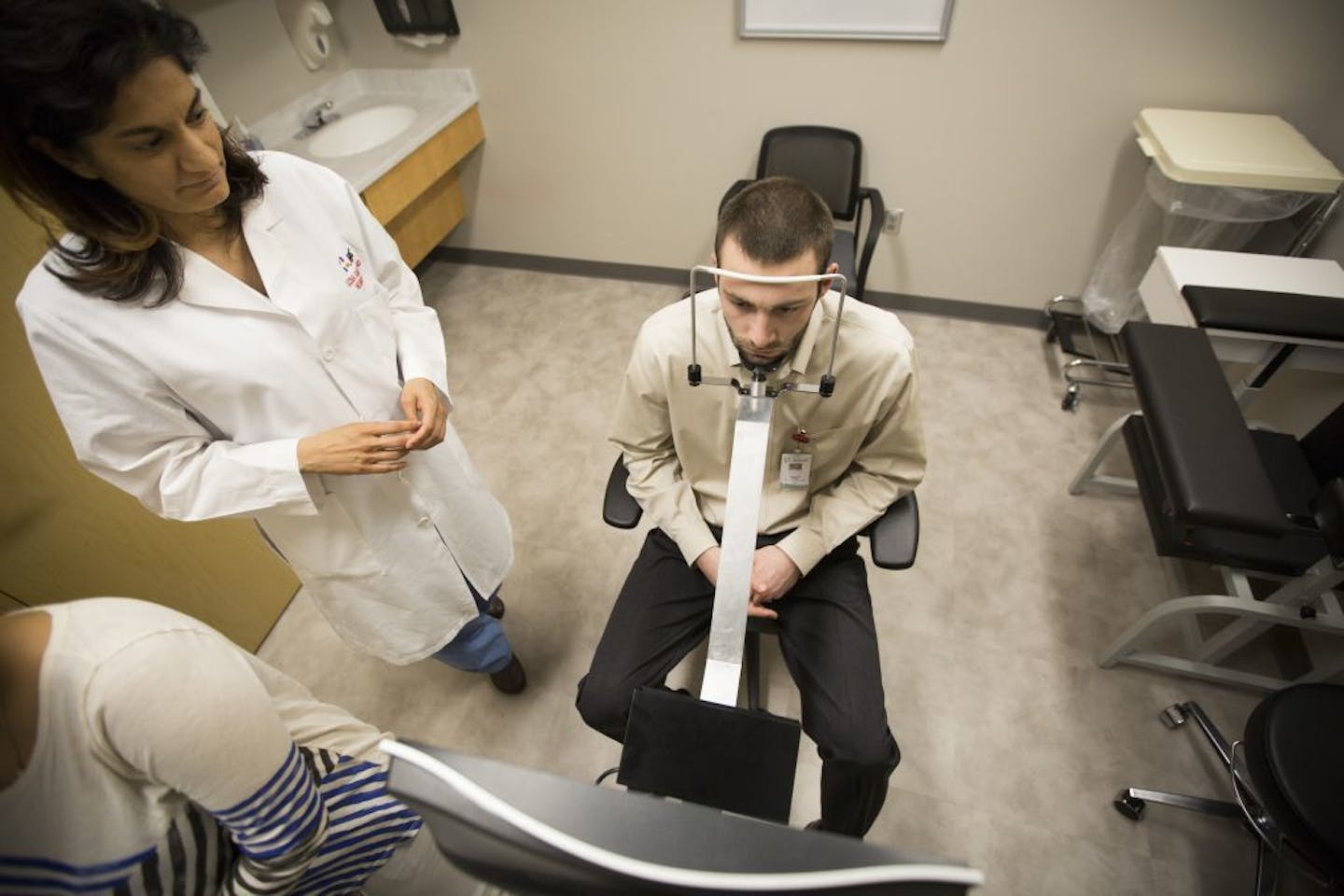 Dr. Uzma Samadani, left, watched as research assistant Sam Daly sat through an eye test at HCMC on Wednesday, March 9, 2016, in Minneapolis, Minn. HCMC has been conducting eye tests on study participants including Daly, who works in the lab and is a former athlete, as part of research to identify better ways to detect concussion injuries and their long-term consequences. The test tracks both eye movements with a camera as a video moves around the screen.