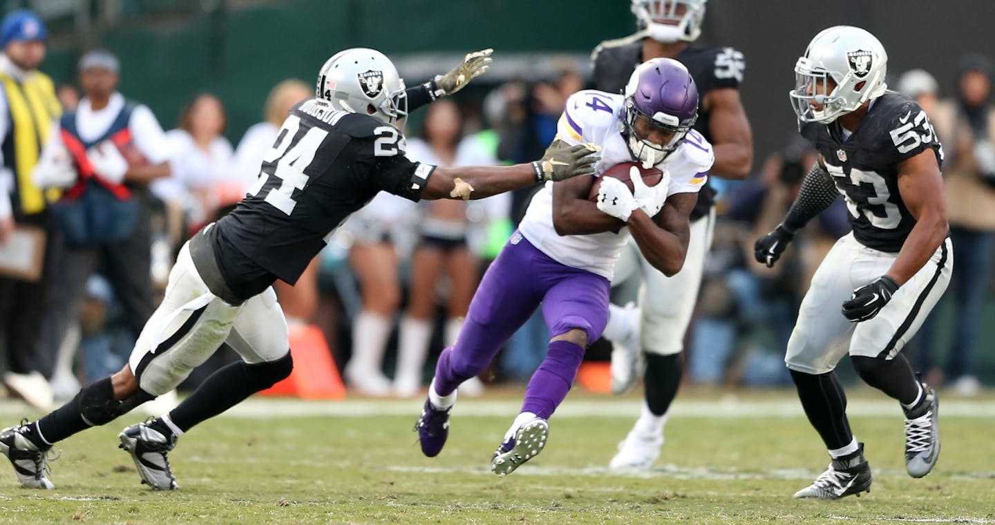 Vikings wide receiver Stefon Diggs split Raiders defenders Charles Woodson (24) and Malcolm Smith (53), picking up a first down in the forth quarter against the Raiders on Sunday.