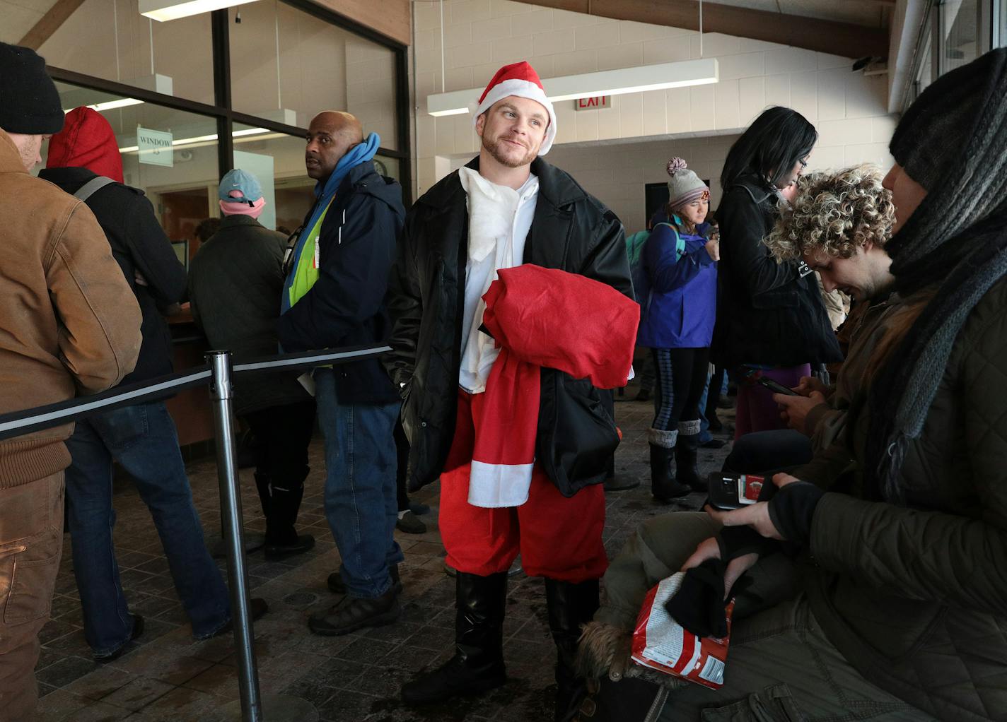 Darren Nelson, dressed as Santa Claus, talks with Sarah Olson, right, as he stands in line to retrieve his friend's car Tuesday. ] ANTHONY SOUFFLE &#x2022; anthony.souffle@startribune.com Car owners retrieve their vehicles that were towed during the weekend's snow emergency Tuesday, Dec. 13, 2016 at the city impound lot in Minneapolis.