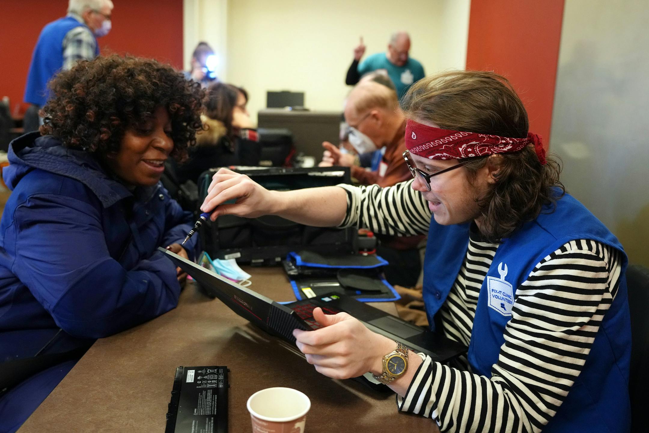 Keiona Cook talks with Caleb Ihla as he replaces the cracked screen on her business laptop during a Ramsey County fix-it clinic Saturday, Nov. 19, 2022 at the Ramsey County Library in Maplewood, Minn. Cook's laptop had been broken for about two years and though she had ordered a replacement screen, she wanted a professional to install it.