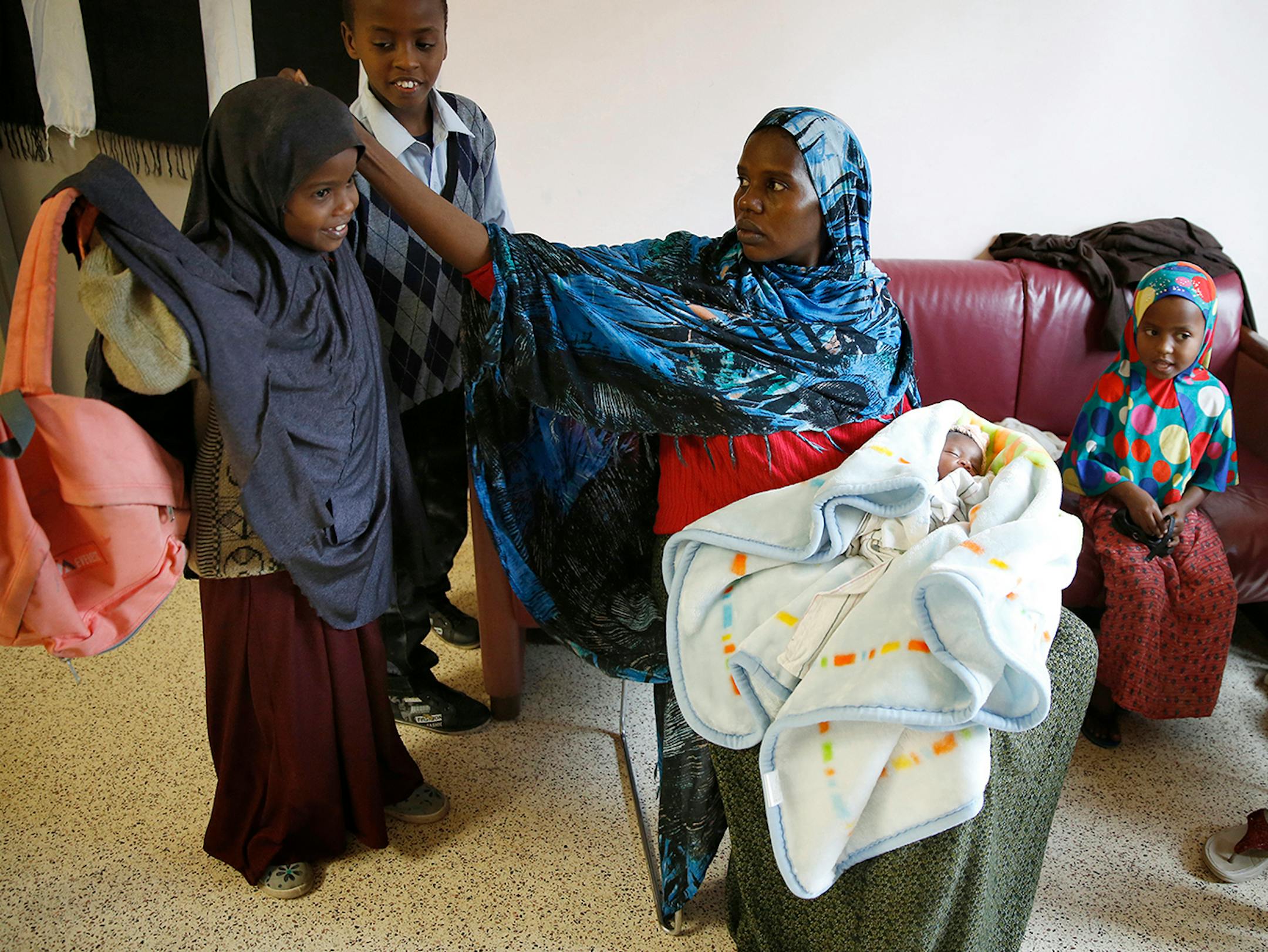 Recent Somali immigrant Mahado Mohamed, center, greets her children home from school Ugbad Shukri, from left, 7, and Antar Shukri, 10, with one-week-old Ifrah Shukri, in her arms and daughters Hafifa Shukri, 4, and Ikra Shukri, 1, by her side in their apartment at Mary's Place transitional apartments in downtown Minneapolis. The family arrived in the United States four months ago, first landing in Connecticut before coming to Minnesota. ] LEILA NAVIDI leila.navidi@startribune.com / BACKGROUND IN