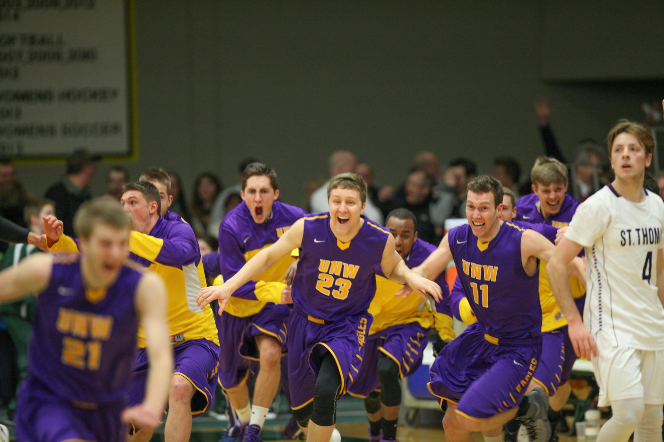 Northwestern (St. Paul) men's basketball players, including Thomas Shephard (23) and Caleb Janson (11), chased after Porter Morrell, left, after Morrell hit the winning three-pointer at the buzzer to send the Eagles past St. Thomas in the first round of the NCAA Division III men's basketball tournament Saturday in De Pere, Wis.