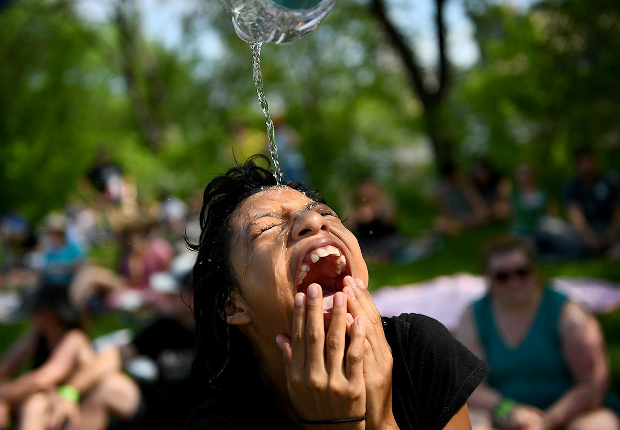 Edward Schroering, not pictured, of Tampa Bay, dumped a bottle of water on the head of his daughter Marisa, 11, while relaxing near some shade at Boom Island Park Saturday. Water was in high demand, with lines hundreds of feet long at hydration stations.
