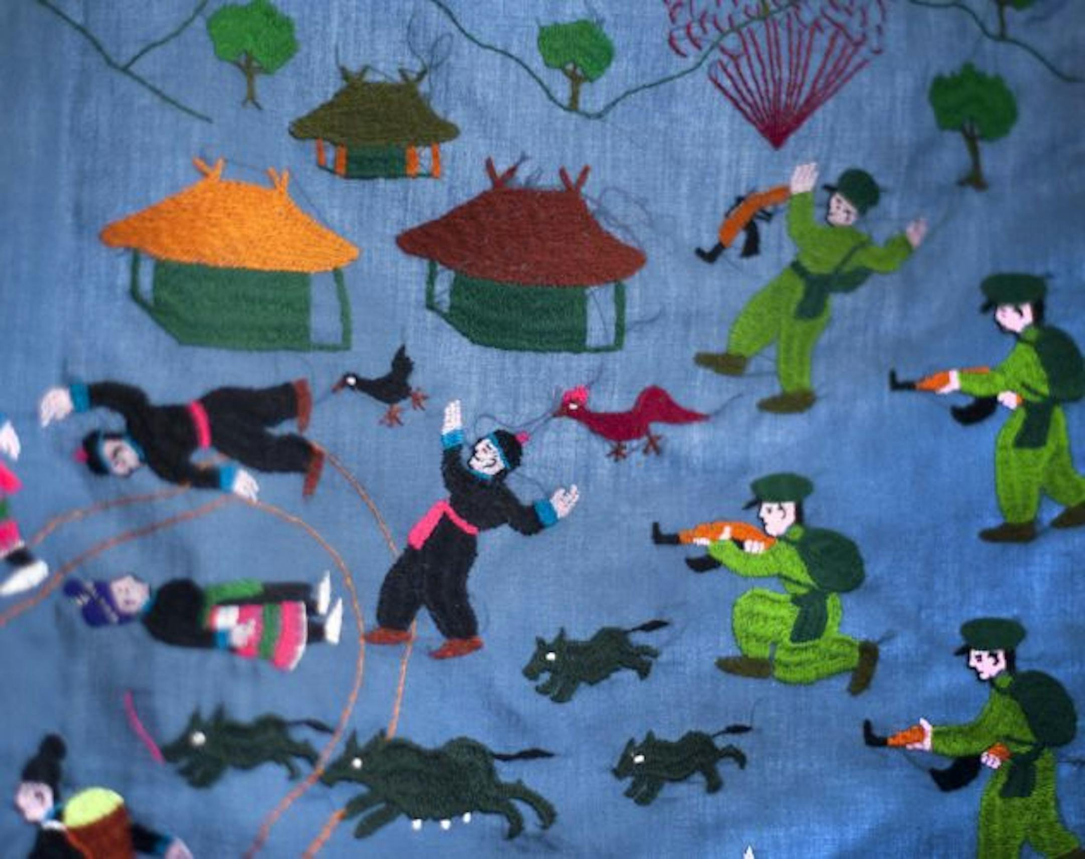 This Hmong story cloth shows North Vietnamese soldiers chasing Hmong people through their village.