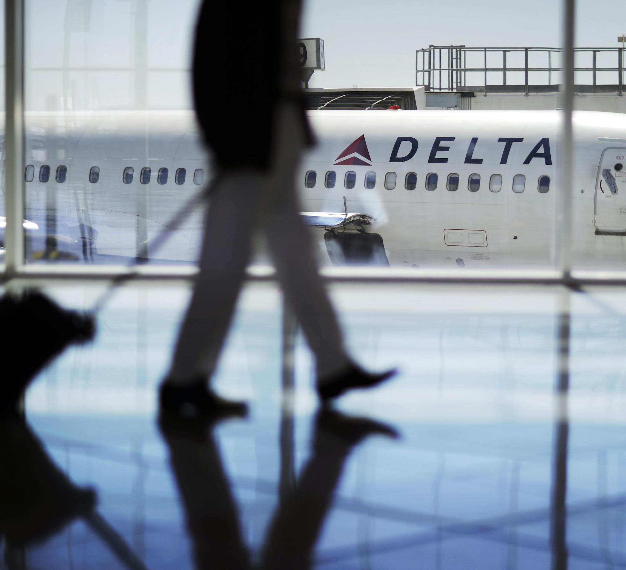 In this Thursday, Oct. 13, 2016, photo, a Delta Air Lines jet sits at a gate at Hartsfield-Jackson Atlanta International Airport in Atlanta. Delta announced Thursday, Dec. 8, 2016, that the airline is rolling out new free snacks for customers in the main cabin, including brand-name yogurt bars and pretzels. Some will come in larger portions than before because, Delta has figured out, that's what customers crave. (AP Photo/David Goldman)