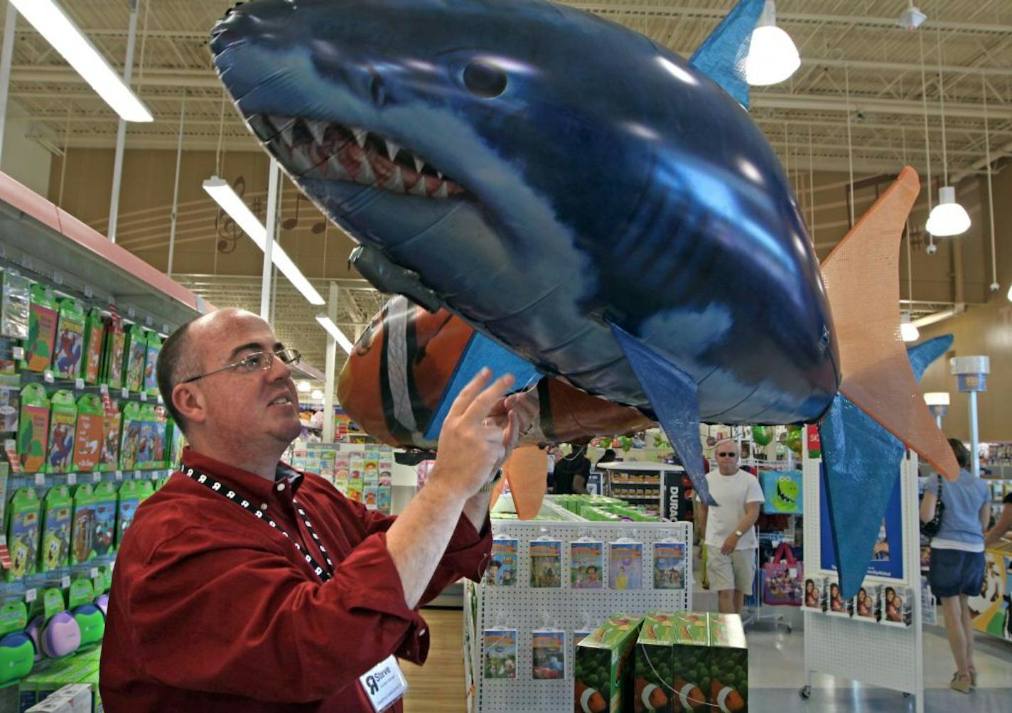 Store manager Steve Koehler held an Air Swimmers flying remote-controlled shark and clownfish as he stood in the new Toys 'R' Us-Babies 'R' Us superstore in Minnetonka. The company hopes to increase efficiency and offer a more diverse assortment of products by combining the stores.