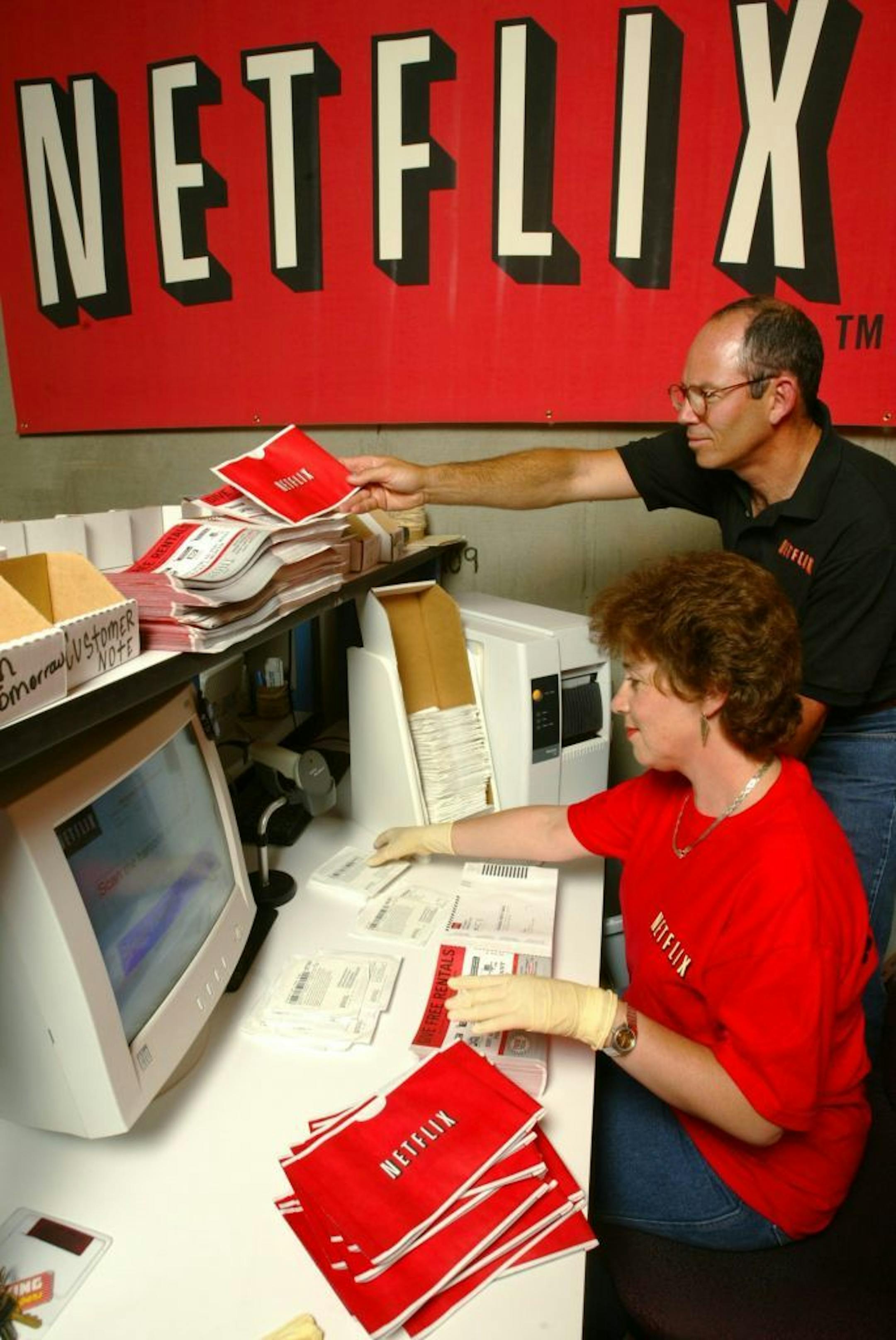 FILE - In this July 11, 2002, file photo, Netflix co-founder Marc Randolph looks over the shoulder of Natalya Kontorovich at Netflix Inc.'s Denver distribution site. A new book,"Netflixed: The Epic Battle for America's Eyeballs," is set to go on sale Thursday, Oct. 11, 2012. The book tries to debunk a widely told tale about the company's origins and paints a polarizing portrait of its star CEO Reed Hastings.