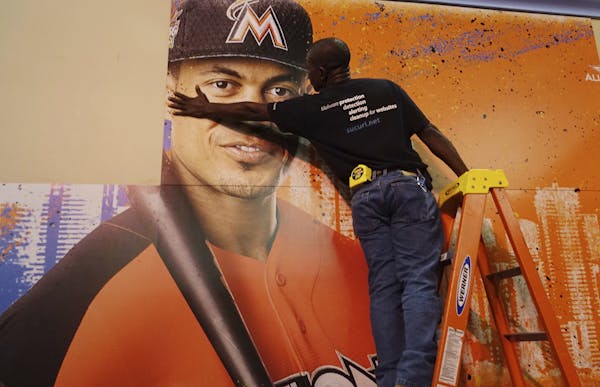 Francois Diesiul hangs a poster bearing the visage of Miami Marlins star Giancarlo Stanton, Thursday, July 6, 2017, at the Miami Beach Convention Cent