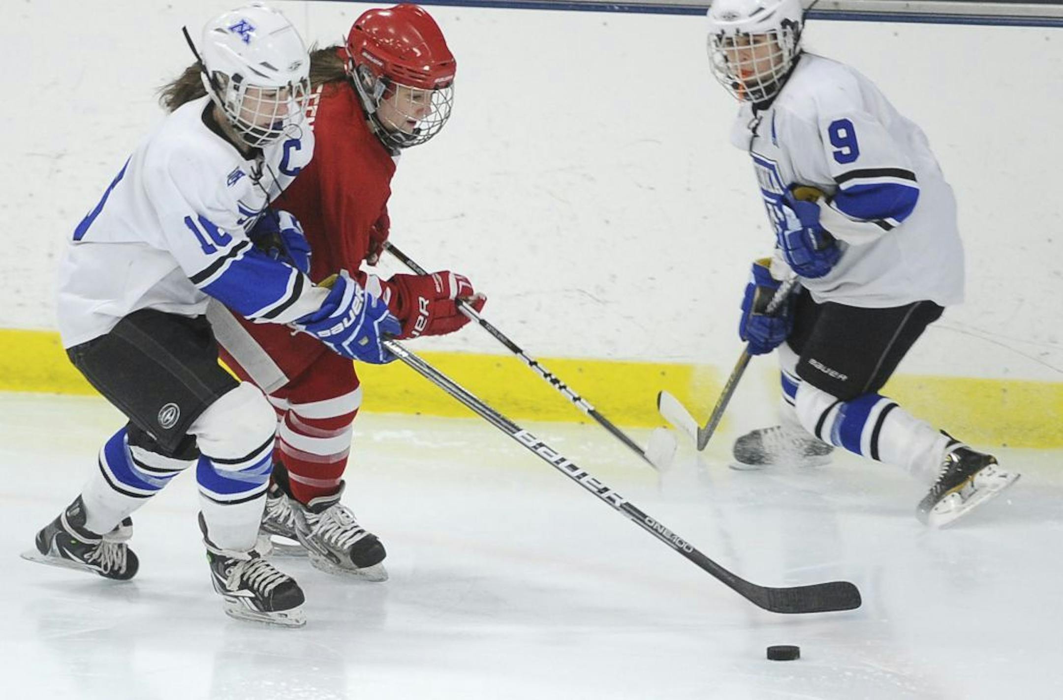 Minnetonka forward Laura Bowman, left, battles Benilde-St. Margaret defender Mekenzie Steffen for the puck on while Minnetonka forward Amy Petersen skates in position.