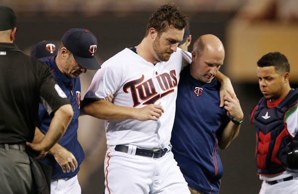 Minnesota Twins pitcher Phil Hughes is helped off the field by trainer Tony Leo, right, and manager Paul Molitor, left, after he was hit in the leg wi