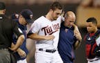 Minnesota Twins pitcher Phil Hughes is helped off the field by trainer Tony Leo, right, and manager Paul Molitor, left, after he was hit in the leg wi