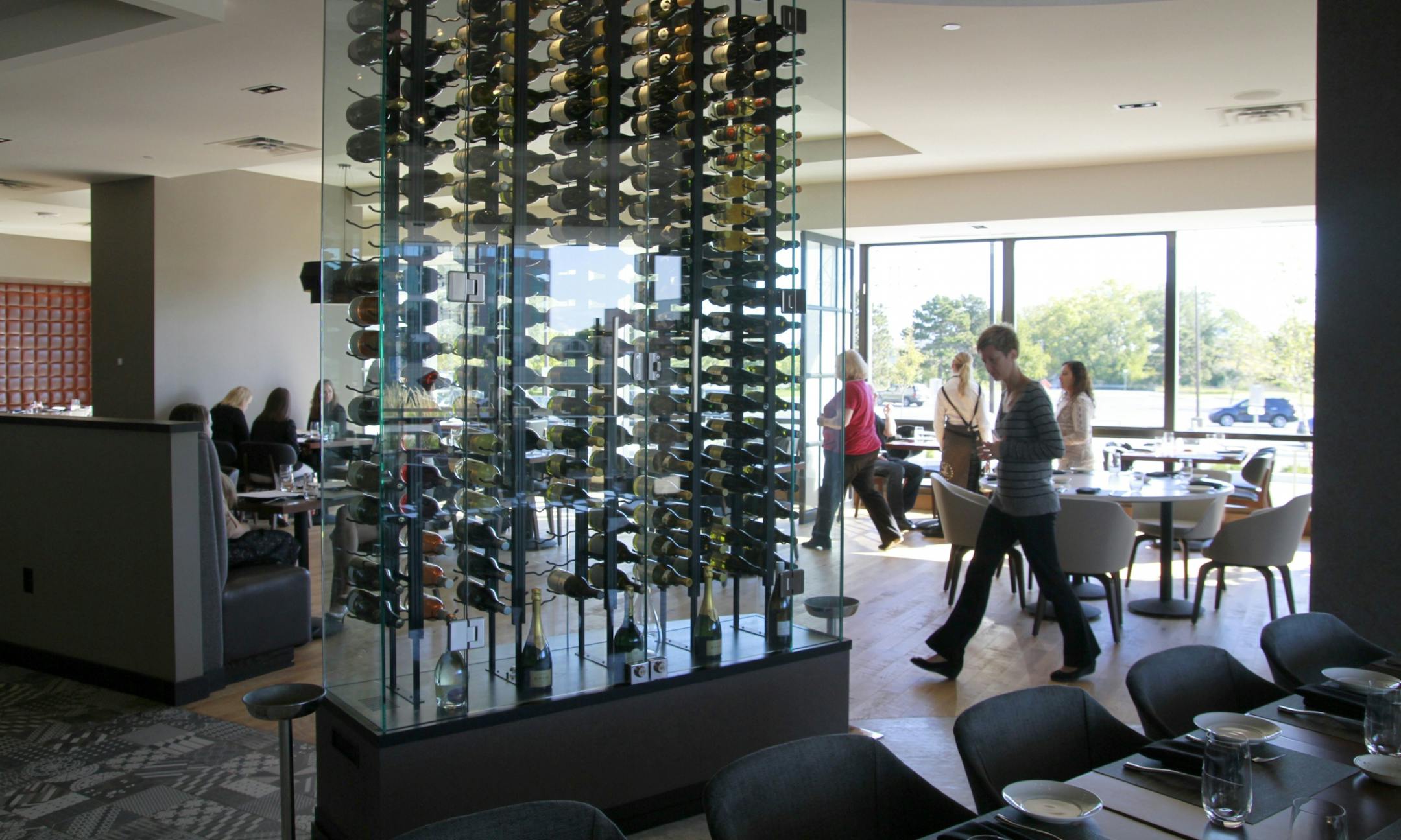 Restaurant review, - Lela, - Interior, see-through wine racks and bright window light in the dining room area
