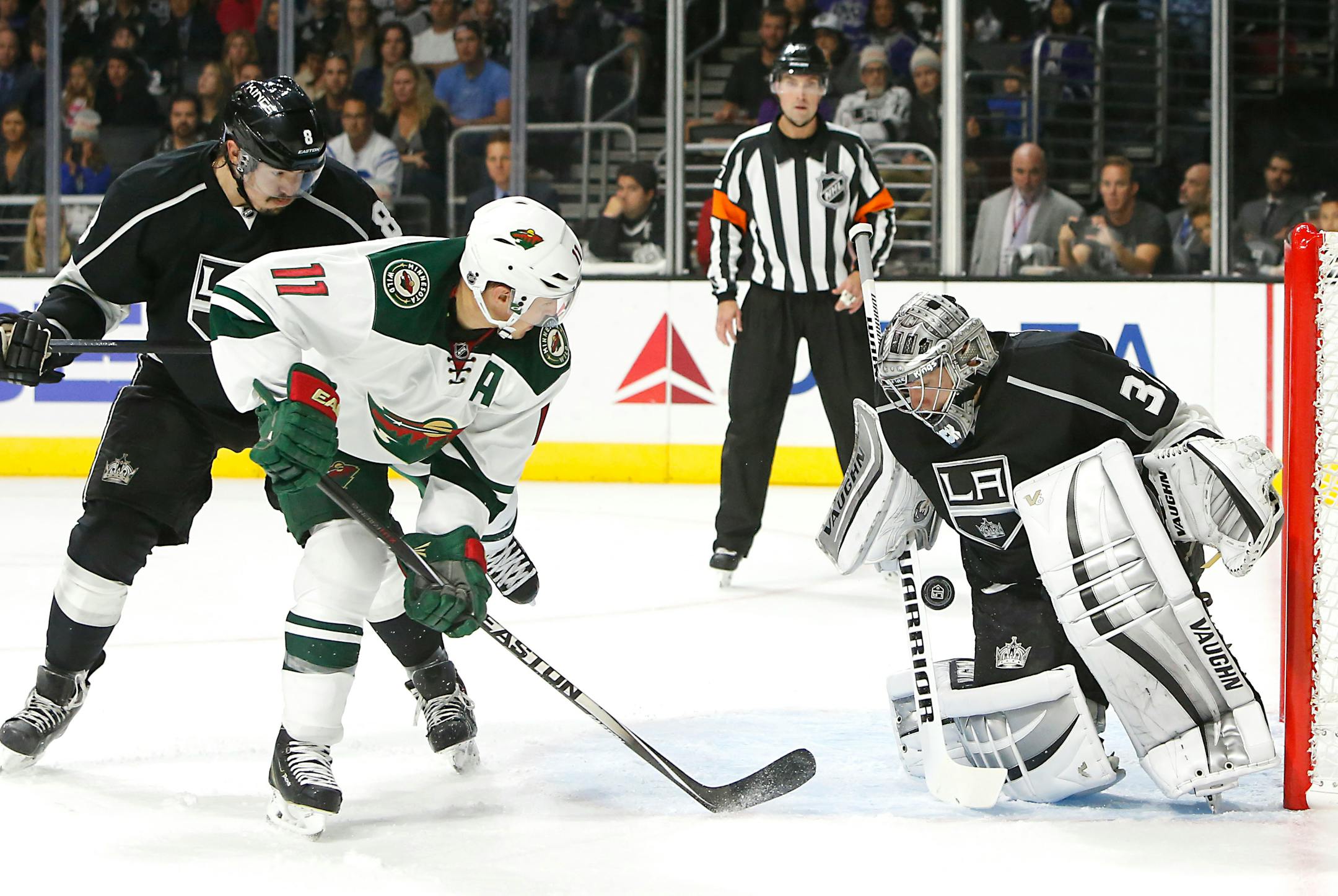Los Angeles Kings goalie Jonathan Quick, right, stops a puck off Minnesota Wild left wing Zach Parise (11) during the third period of an NHL hockey game in Los Angeles on Sunday, Oct. 19, 2014. The Kings won 2-1. (AP Photo/Christine Cotter)