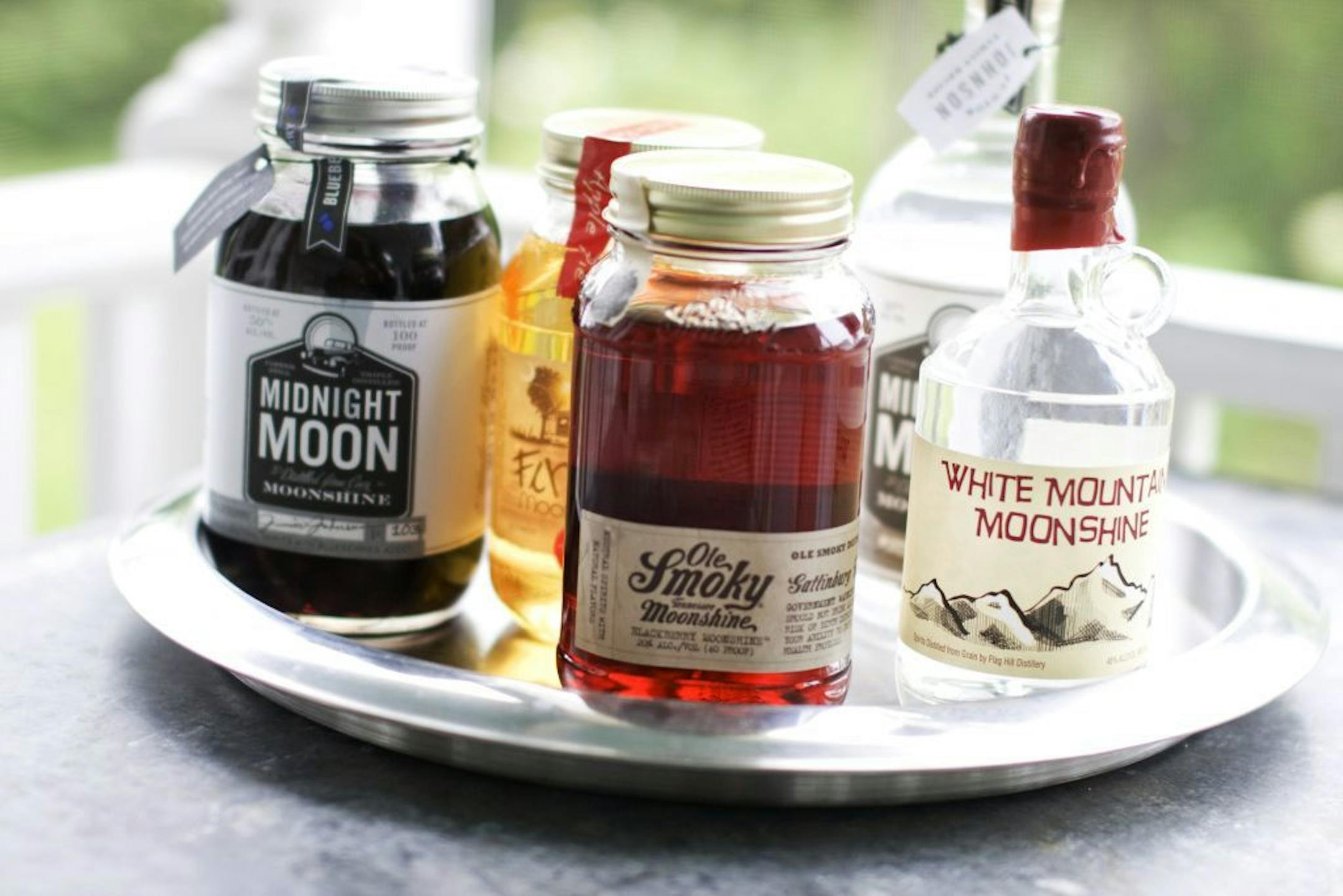 In this image taken on June 10, 2013, from left, Midnight Moon Blueberry, FireFly Moonshine Apple Pie Flavor, Ole Smoky Tennessee Moonshine Blackberry, Midnight Moon Moonshine, and White Mountain Moonshine are shown in Concord, N.H.