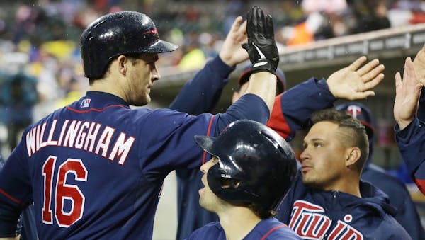 Minnesota Twins' Josh Willingham (16) is congratulated in the dugout after his three-run home run off Detroit Tigers starting pitcher Rick Porcello du