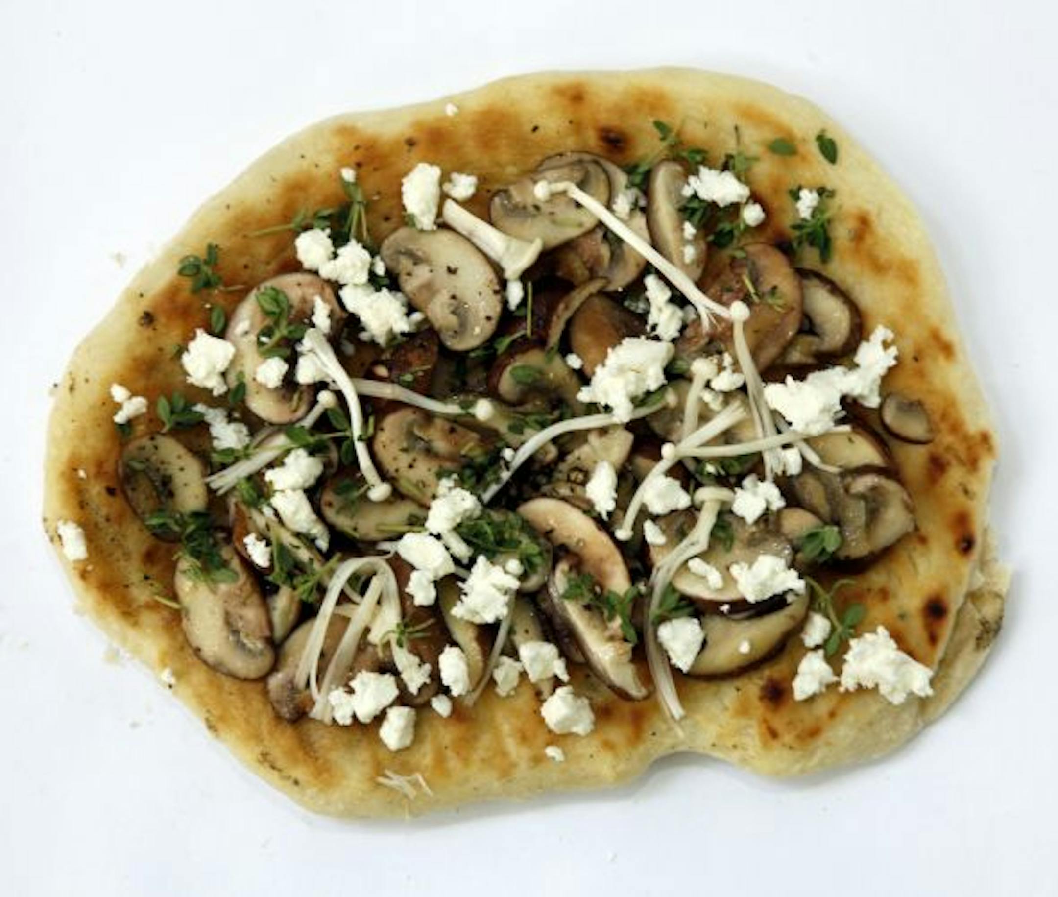 Pizza with olive oil, mixed mushrooms, fresh thyme and crumbled feta cheese.