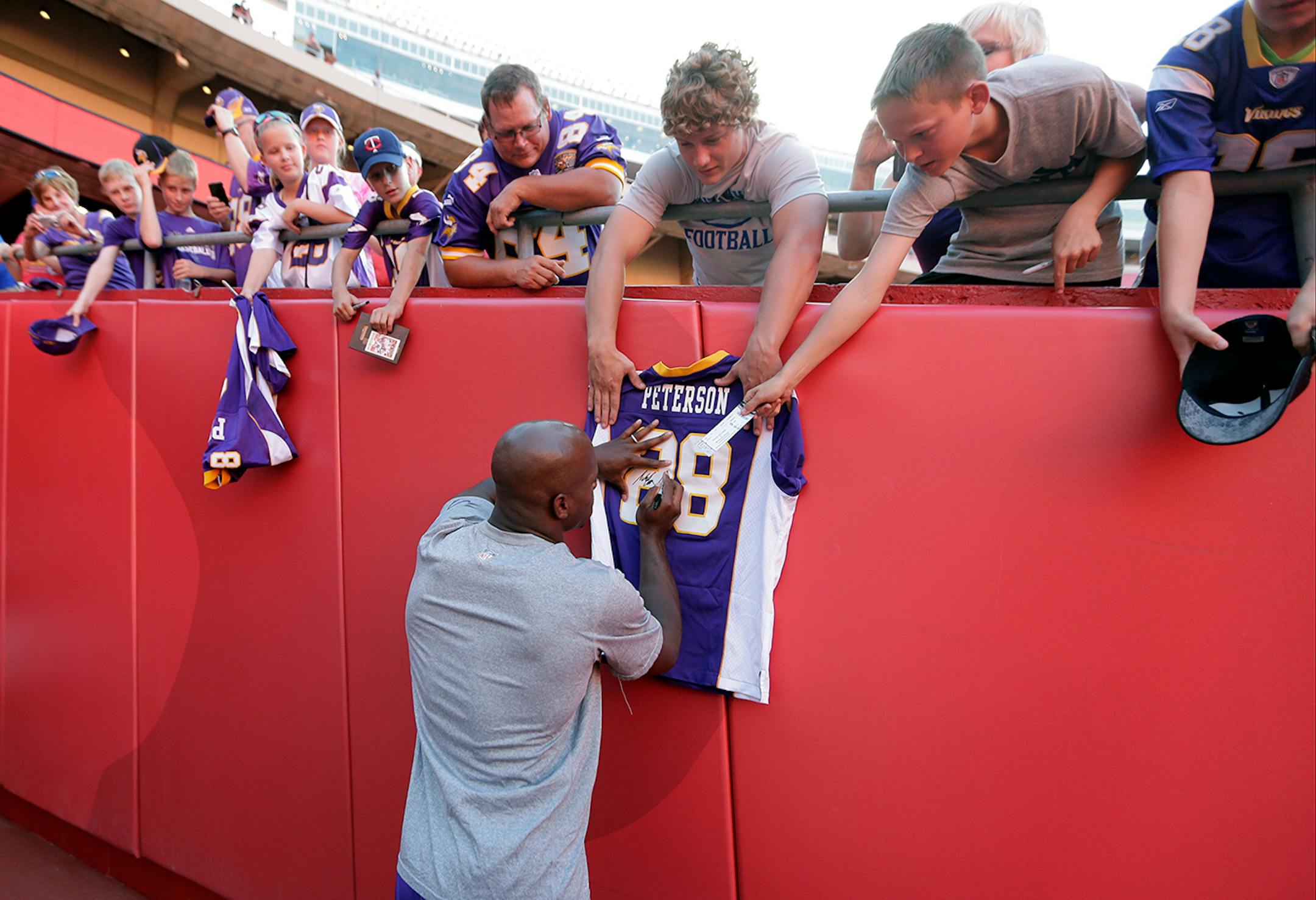 Minnesota Vikings running back Adrian Peterson signs autographs before an NFL preseason football game against the Kansas City Chiefs in Kansas City, Mo., Saturday, Aug. 23, 2014. (AP Photo/Charlie Riedel)