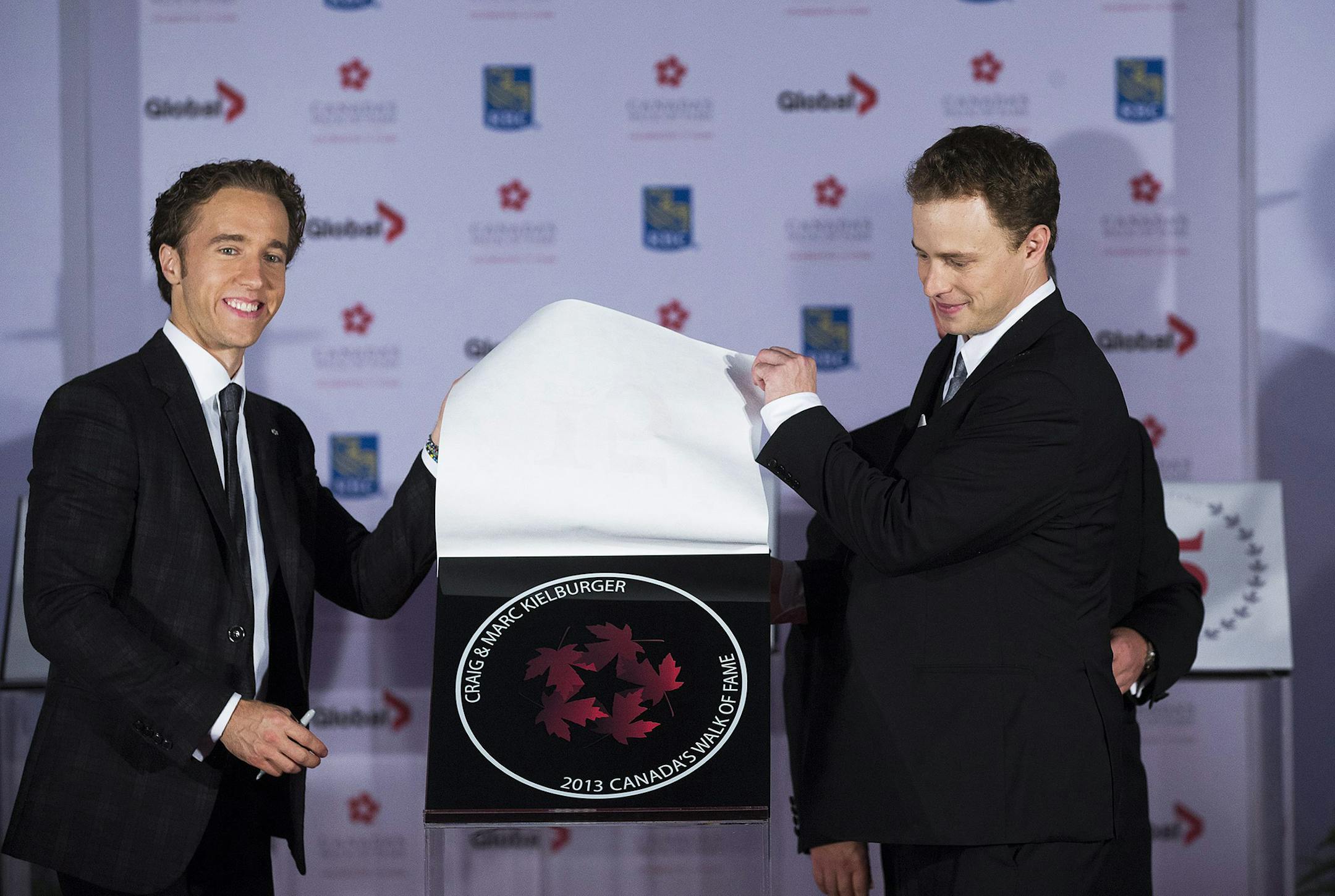 Free The Children cofounders Craig Kielburger, left, and Marc Kielburger, right, posed for a photo during their induction ceremony into Canada's Walk of Fame in Toronto on Saturday, Sept. 21, 2013.