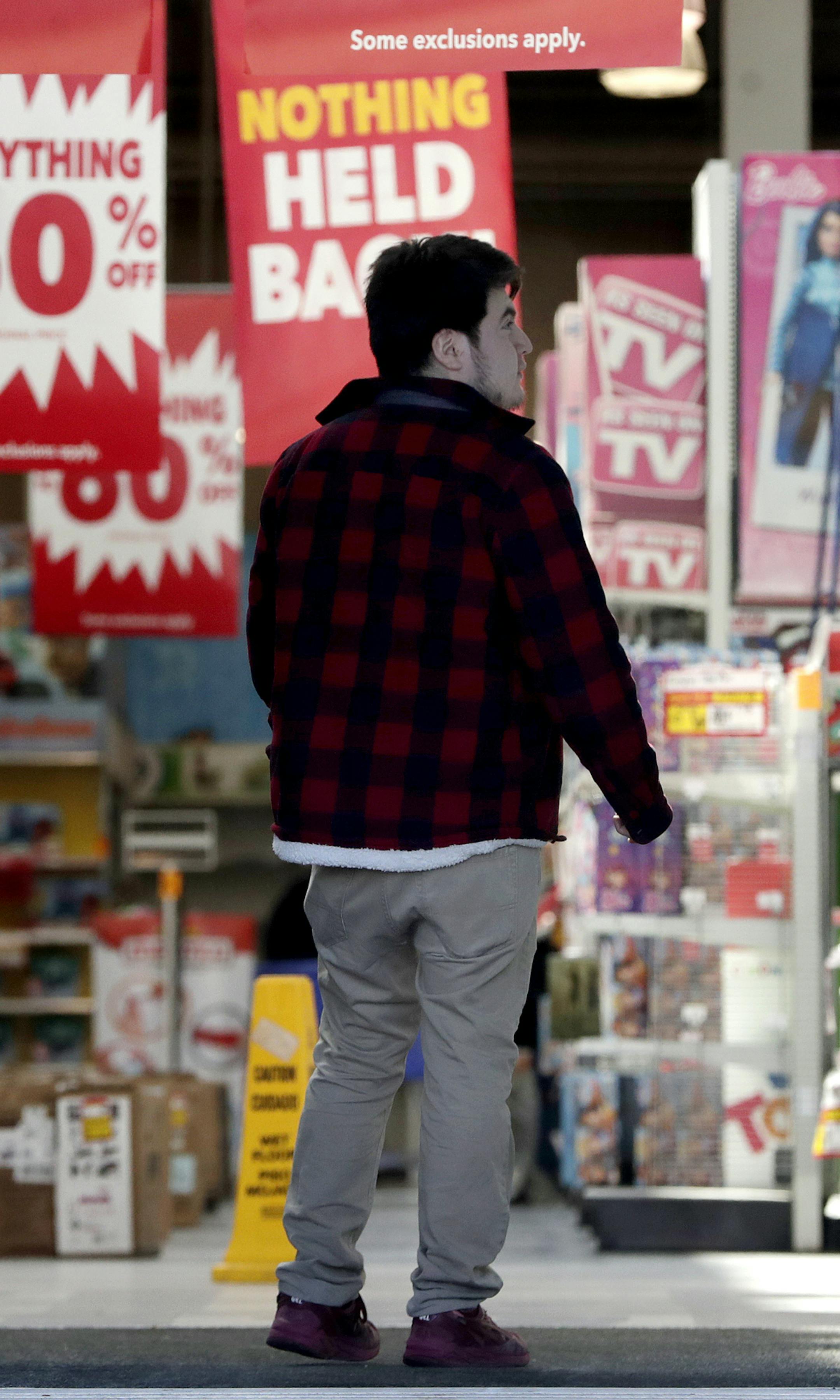 Bargain signs hang from a Toys R US store as a patron enters the location Friday, March 23, 2018, in Elizabeth, N.J. Toys R Us is opening its doors with a going-out-of-business sale, offering clearance discounts at all 735 stores, including Babies R Us. (AP Photo/Julio Cortez)