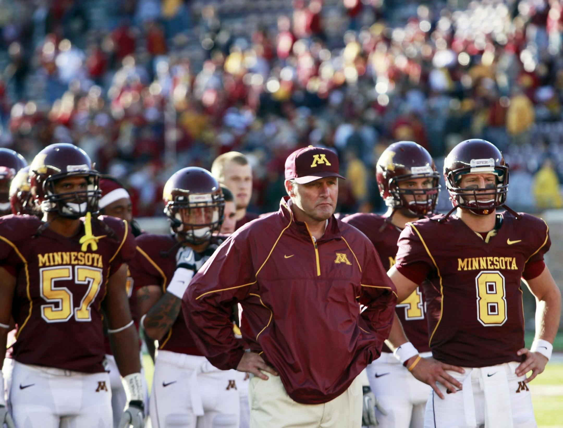 Minnesota coach Tim Brewster and his players listen to the band following the loss.