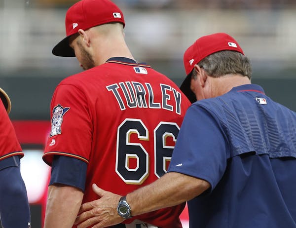 Minnesota Twins pitcher Nink Turley, center, gets support on the mound by pitching coach Neil Allen, right, in the third inning of a baseball game aga