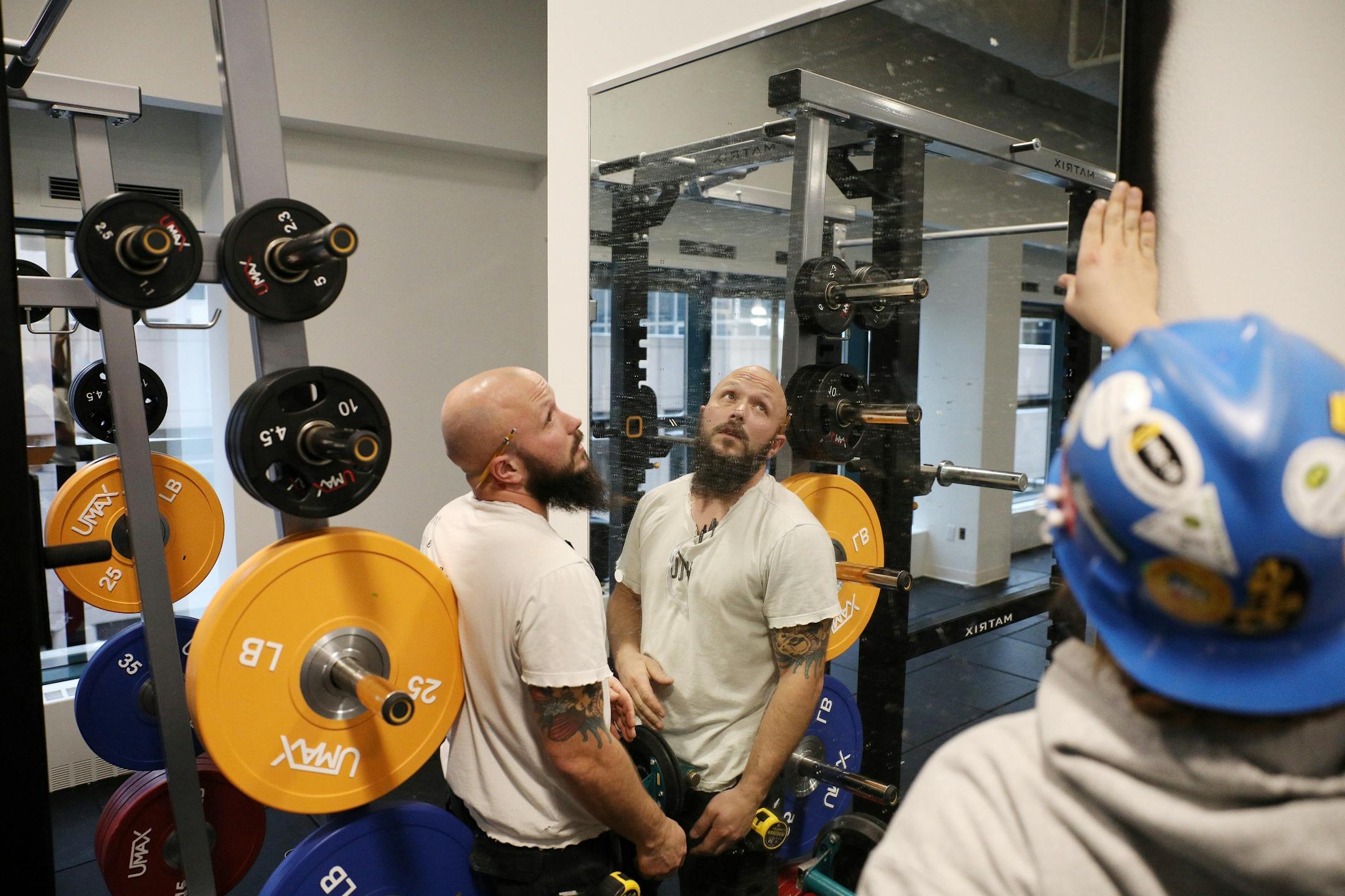 Glazers Tom Lamecker, center, and Brylen Mulvehill installed a set of mirrors in the weight room area.