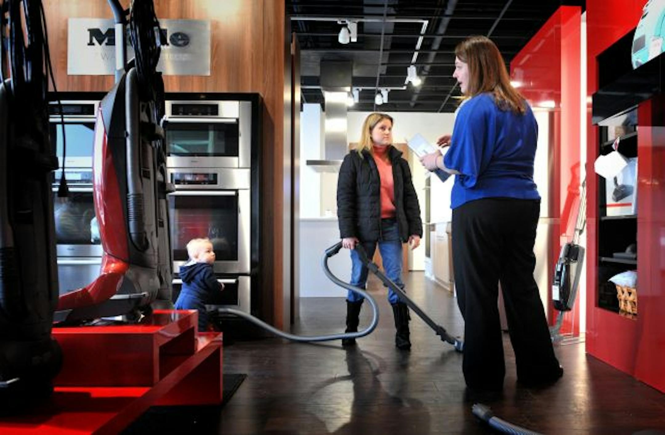 Angela Warner, right, helped Kari Herrgott pick out a vacuum cleaner at the Edina Warners' Stellian store. Kari was there with her husband Chad, 3-year-old daughter Hailey and 10-month-old son Holton, left.