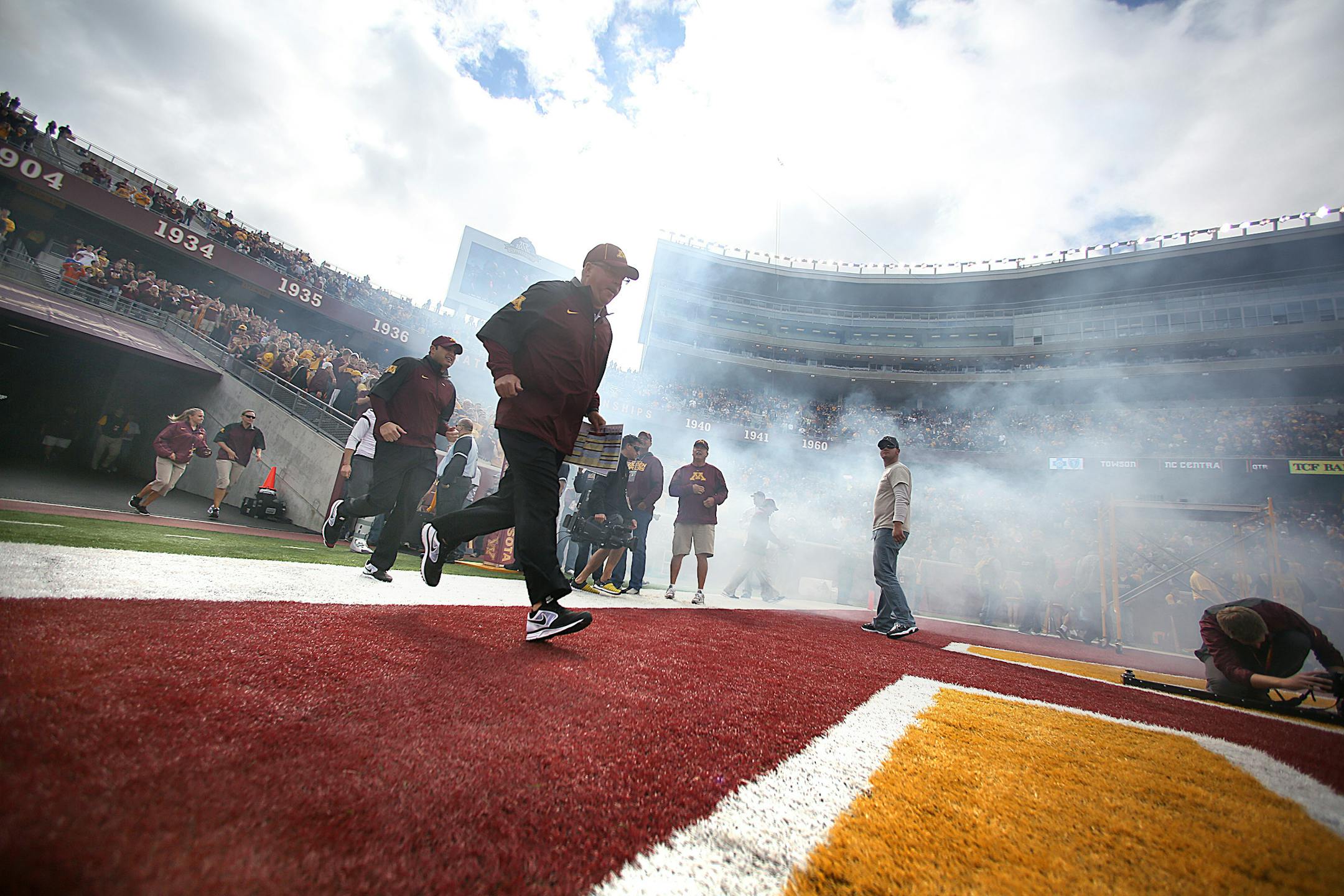 Coach Jerry Kill ran on to the field amid fog and cheers from fans prior to the start of a game in 2013.