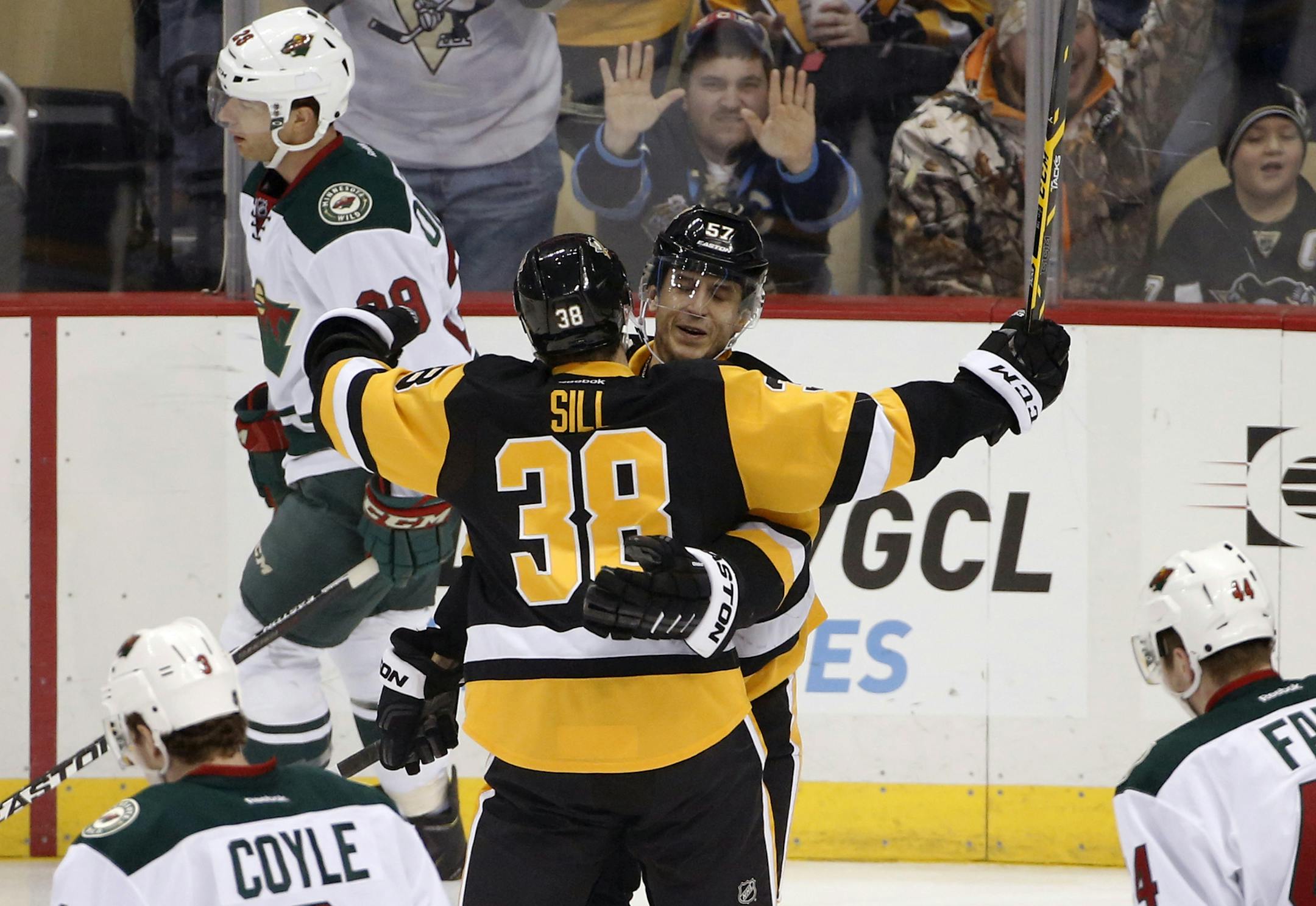 Pittsburgh Penguins' Marcel Goc (57) celebrates his goal with Zach Sill (38), who got his first NHL assist on the score, as Minnesota Wild's Jason Pominville (29) skates back to his bench during the first period of an NHL hockey game in Pittsburgh Tuesday, Jan. 13, 2015. (AP Photo/Gene J. Puskar)